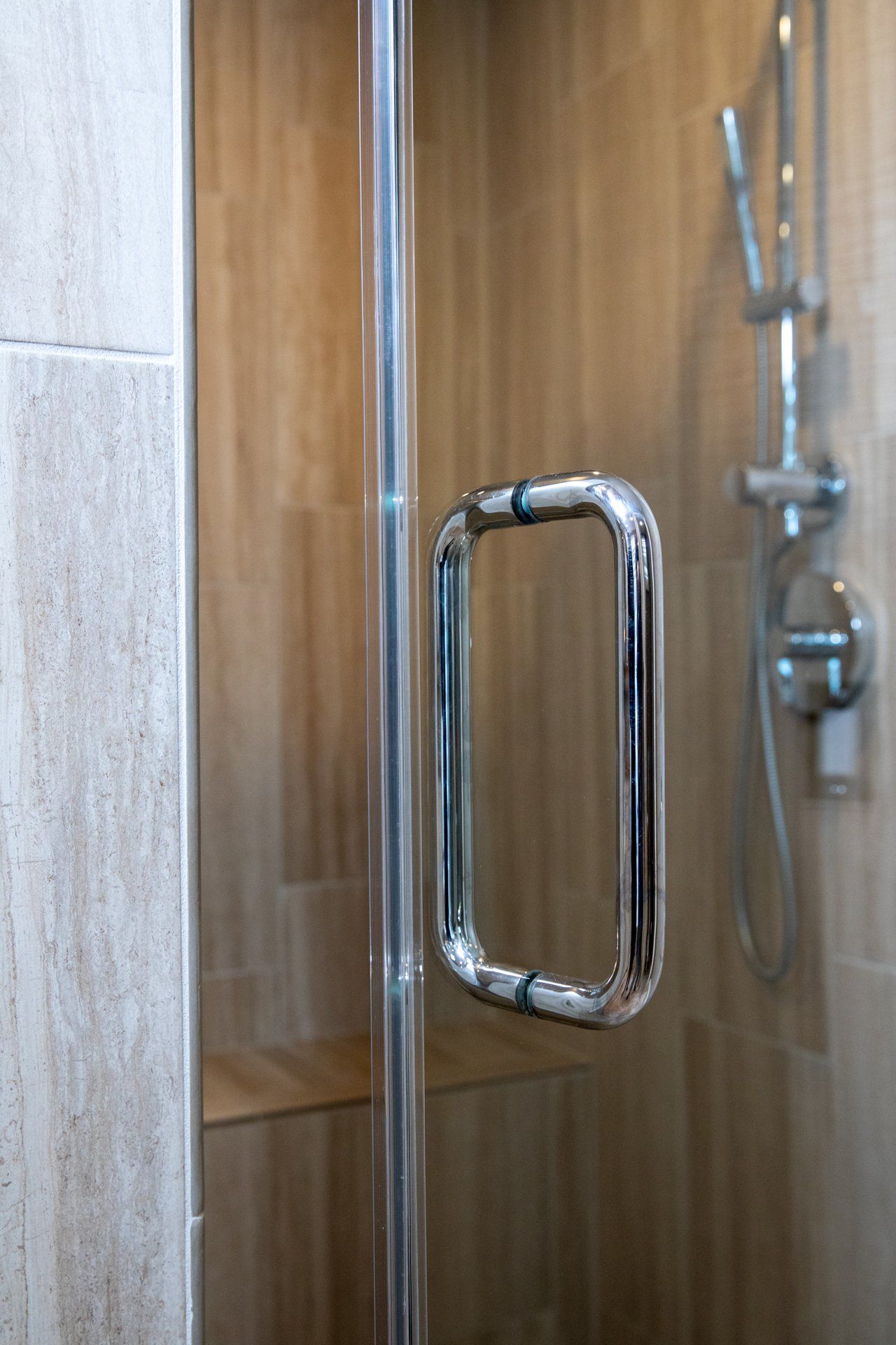 A close up of a shower door with a chrome handle