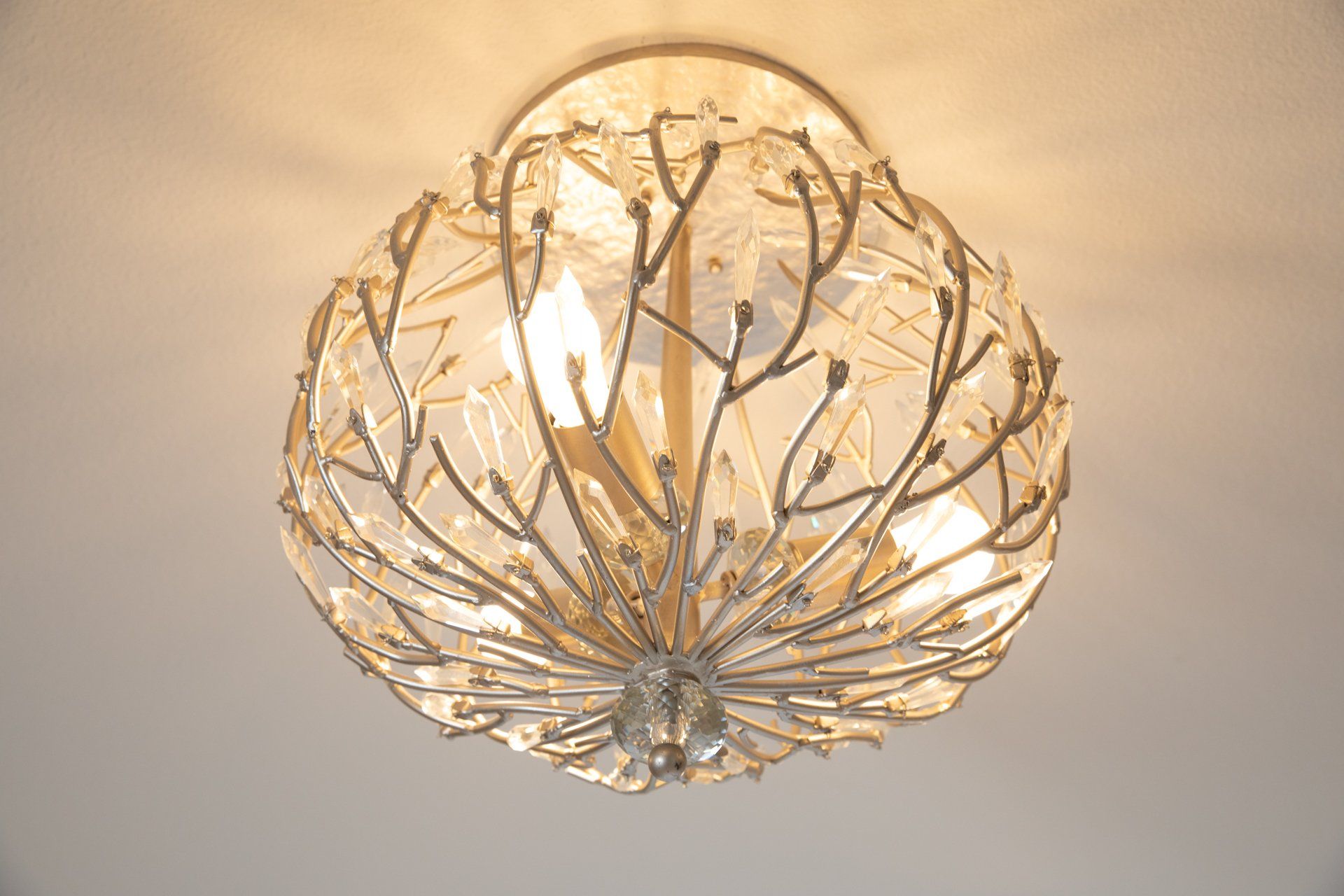 A ceiling light with branches and leaves on it