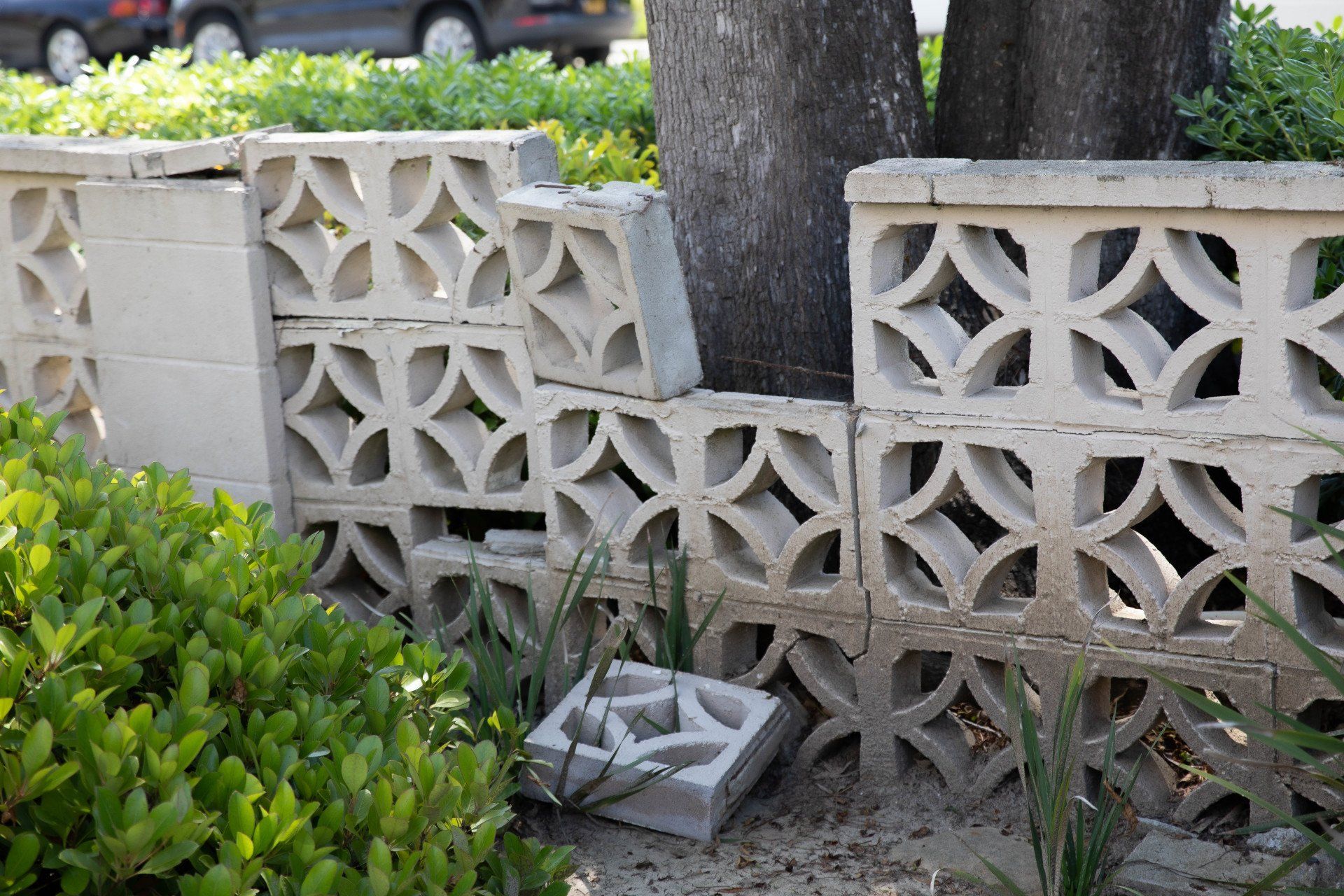 A stack of concrete blocks in a garden with a car in the background
