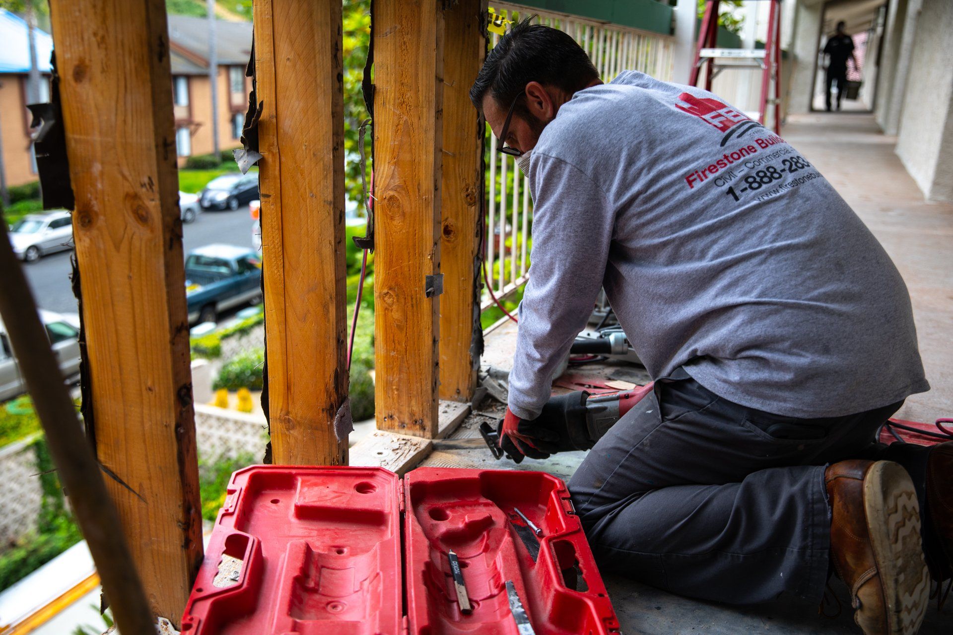 A man is working on a balcony with a toolbox in the foreground