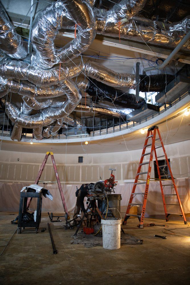 A building under construction with a lot of pipes hanging from the ceiling.