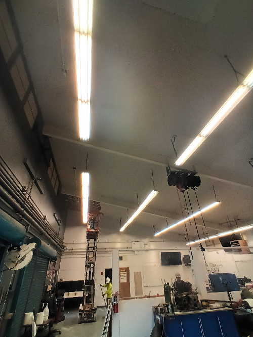 A man on a ladder in a room with lots of lights