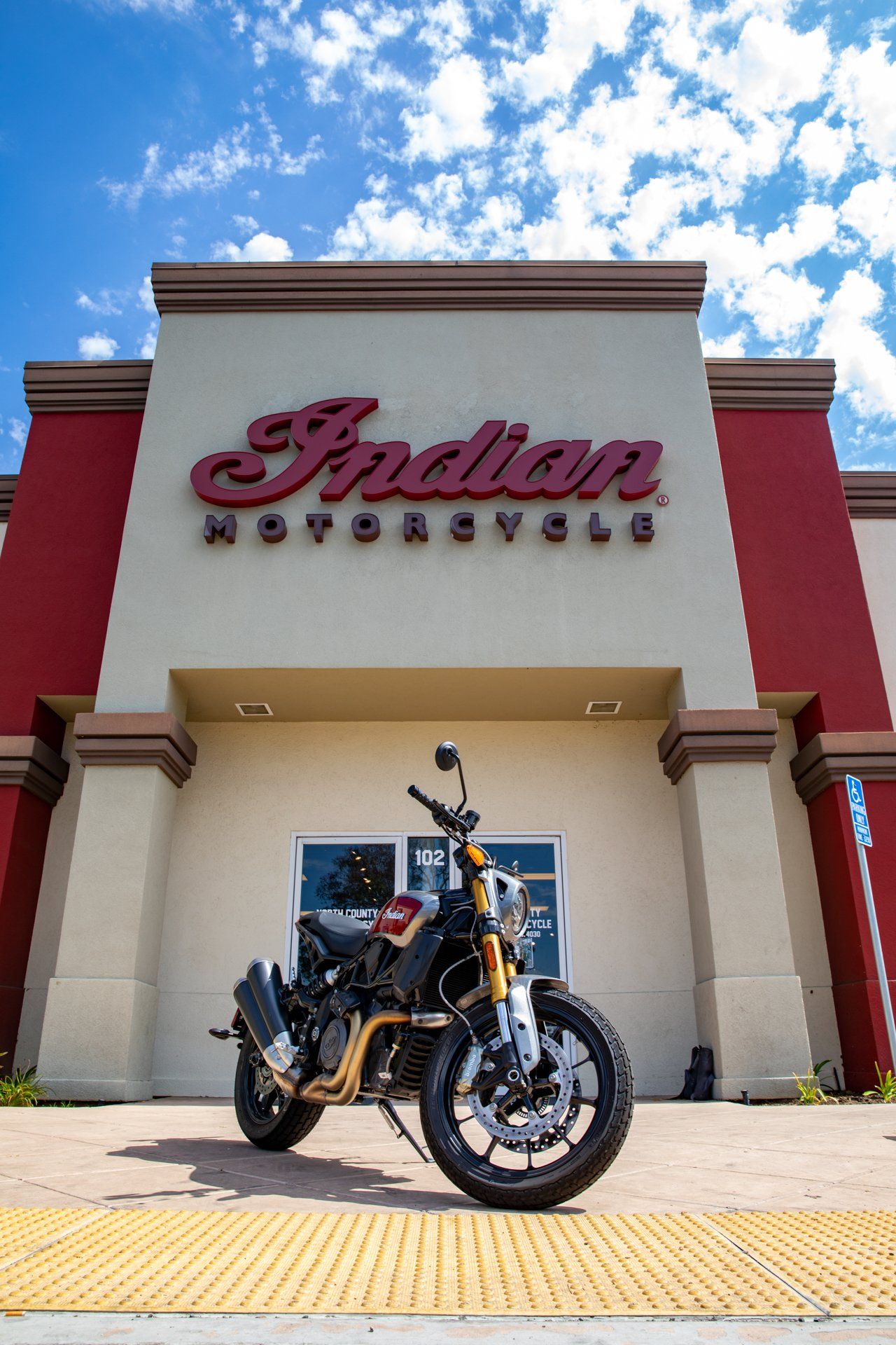 A motorcycle is parked in front of an indian motorcycle store.