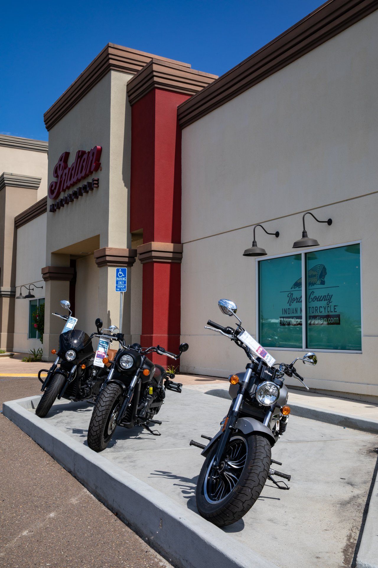 Three motorcycles are parked in front of a building.