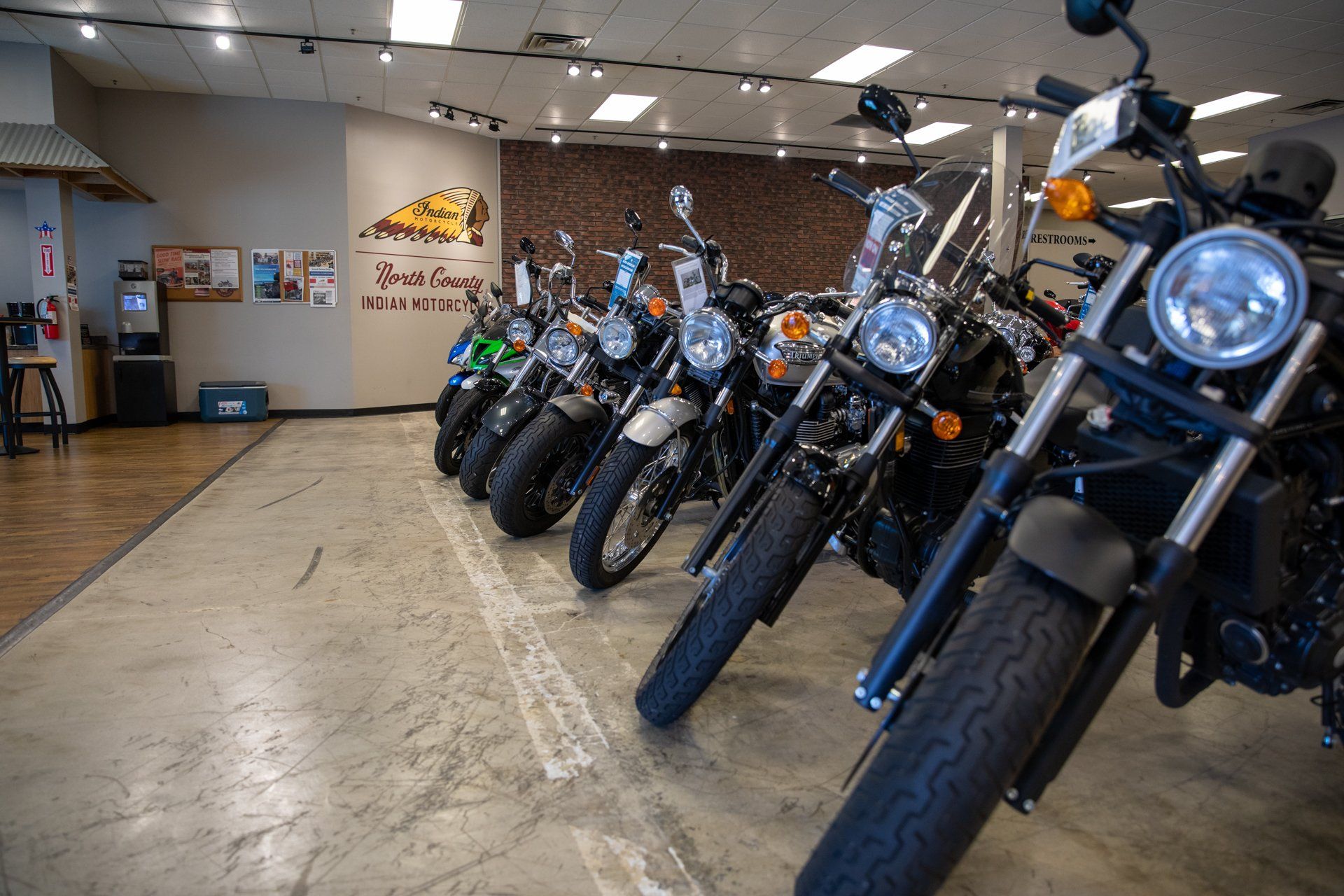 A row of motorcycles are parked in a showroom.