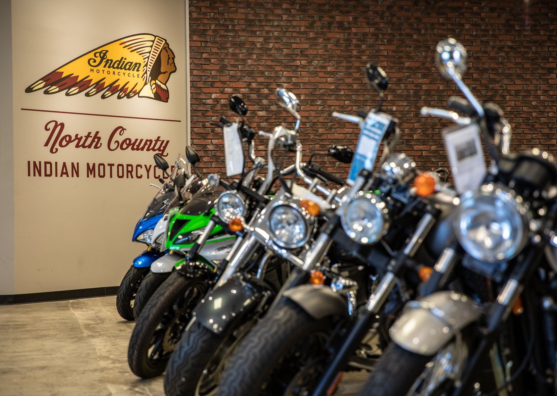 A row of motorcycles are lined up in a showroom.