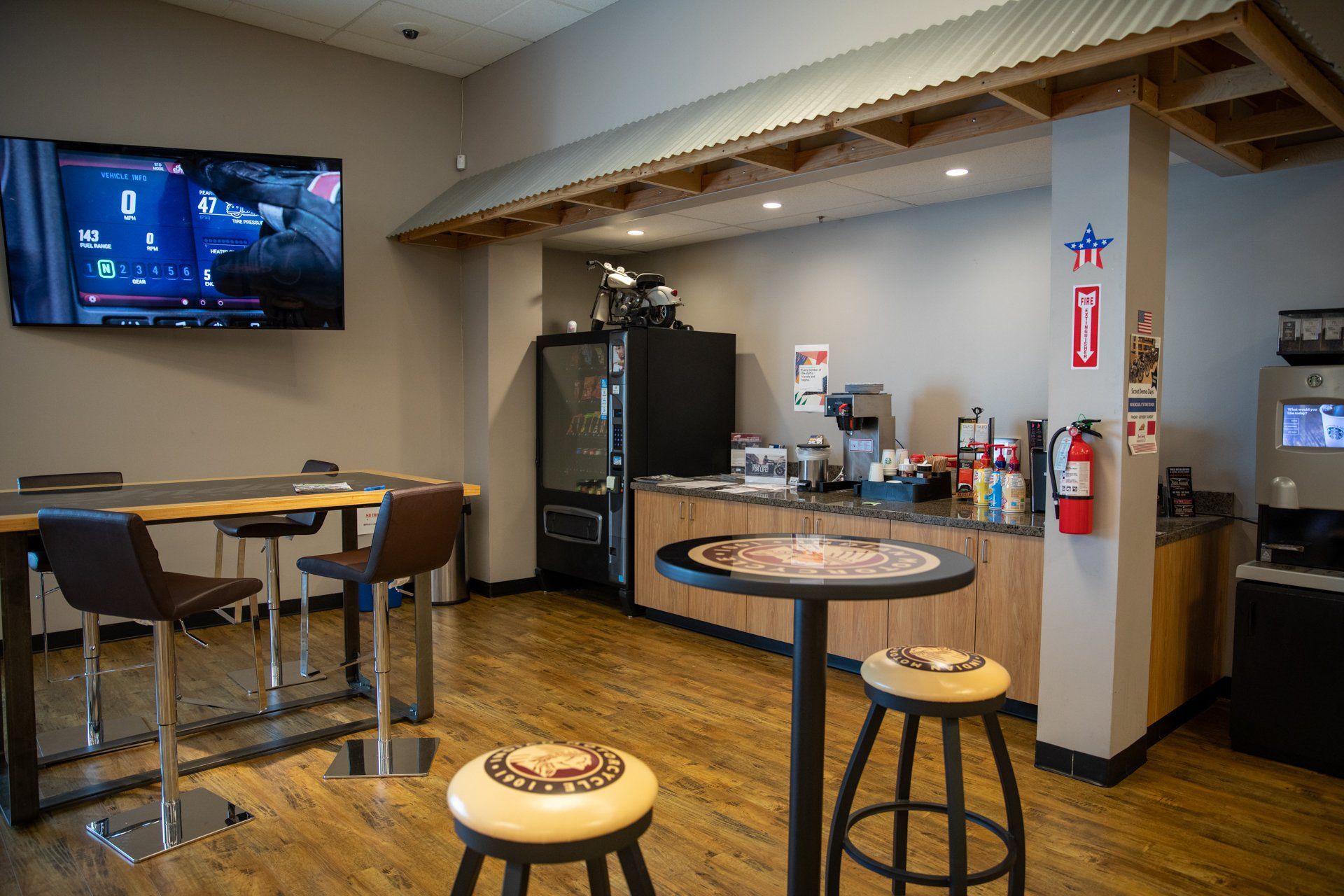 A dining room with tables , chairs , a refrigerator and a flat screen tv.