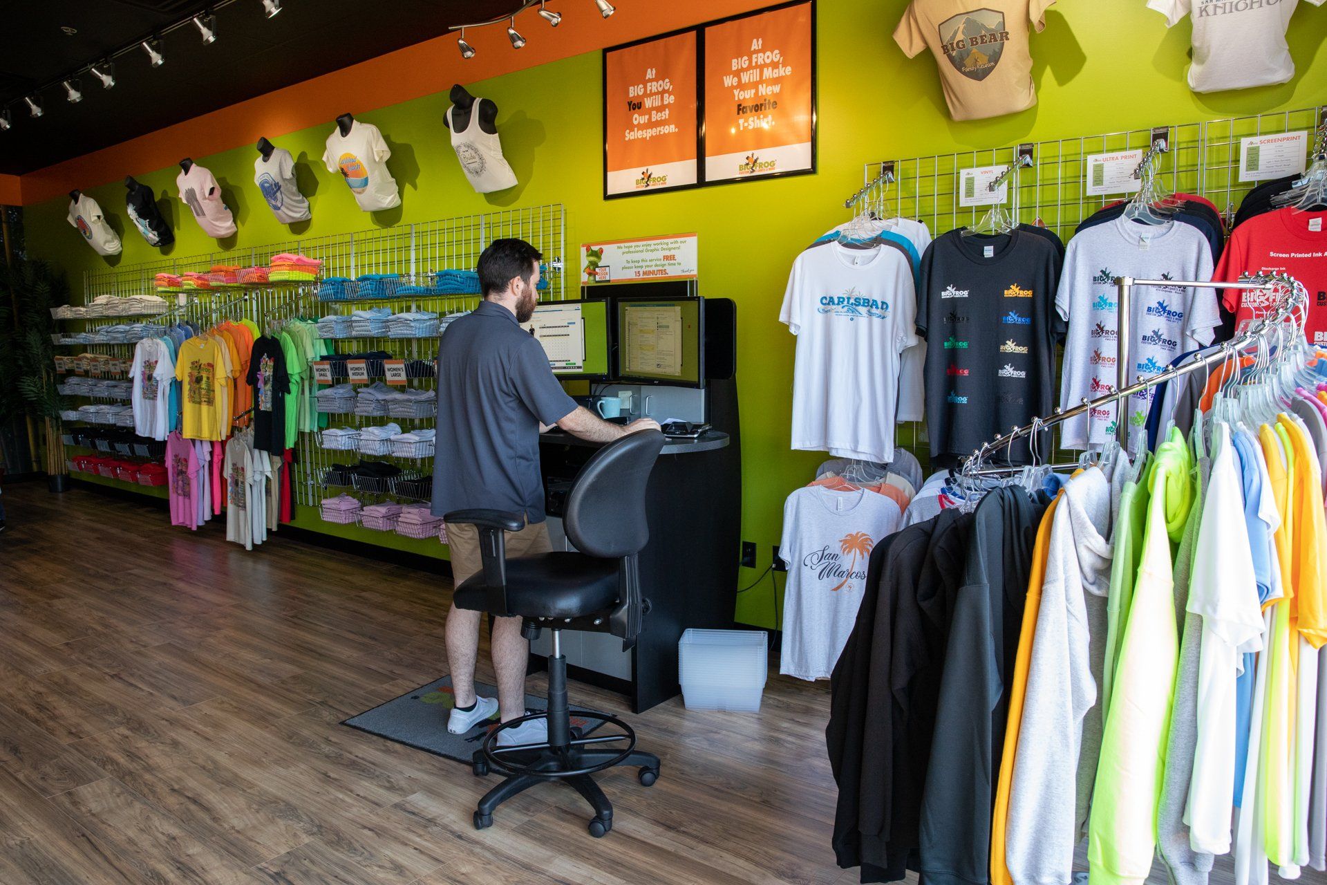 A man is sitting at a desk in a clothing store.