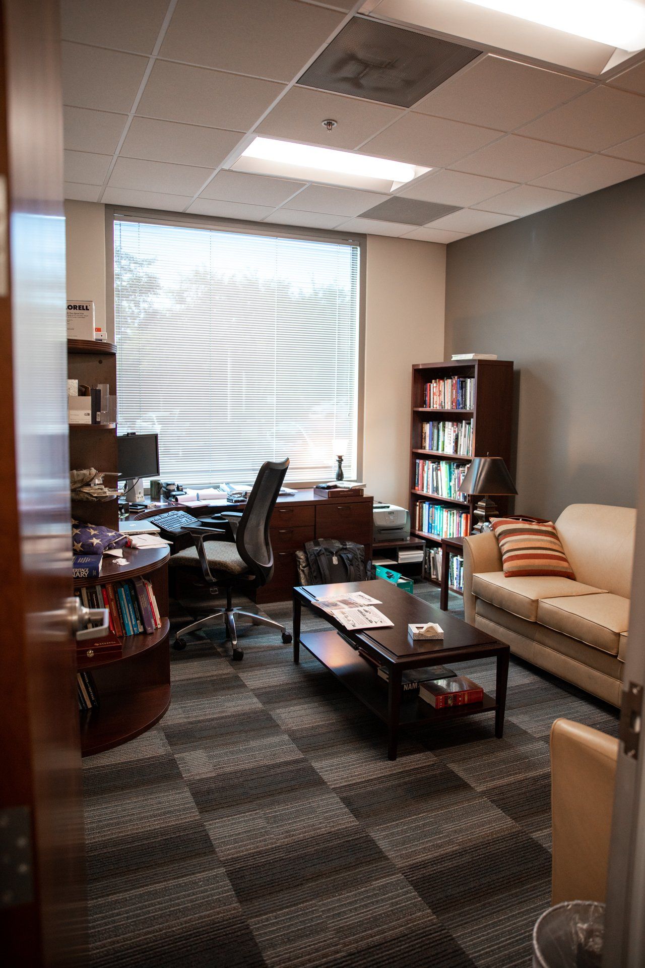 A living room with a couch , desk , coffee table and bookshelf.
