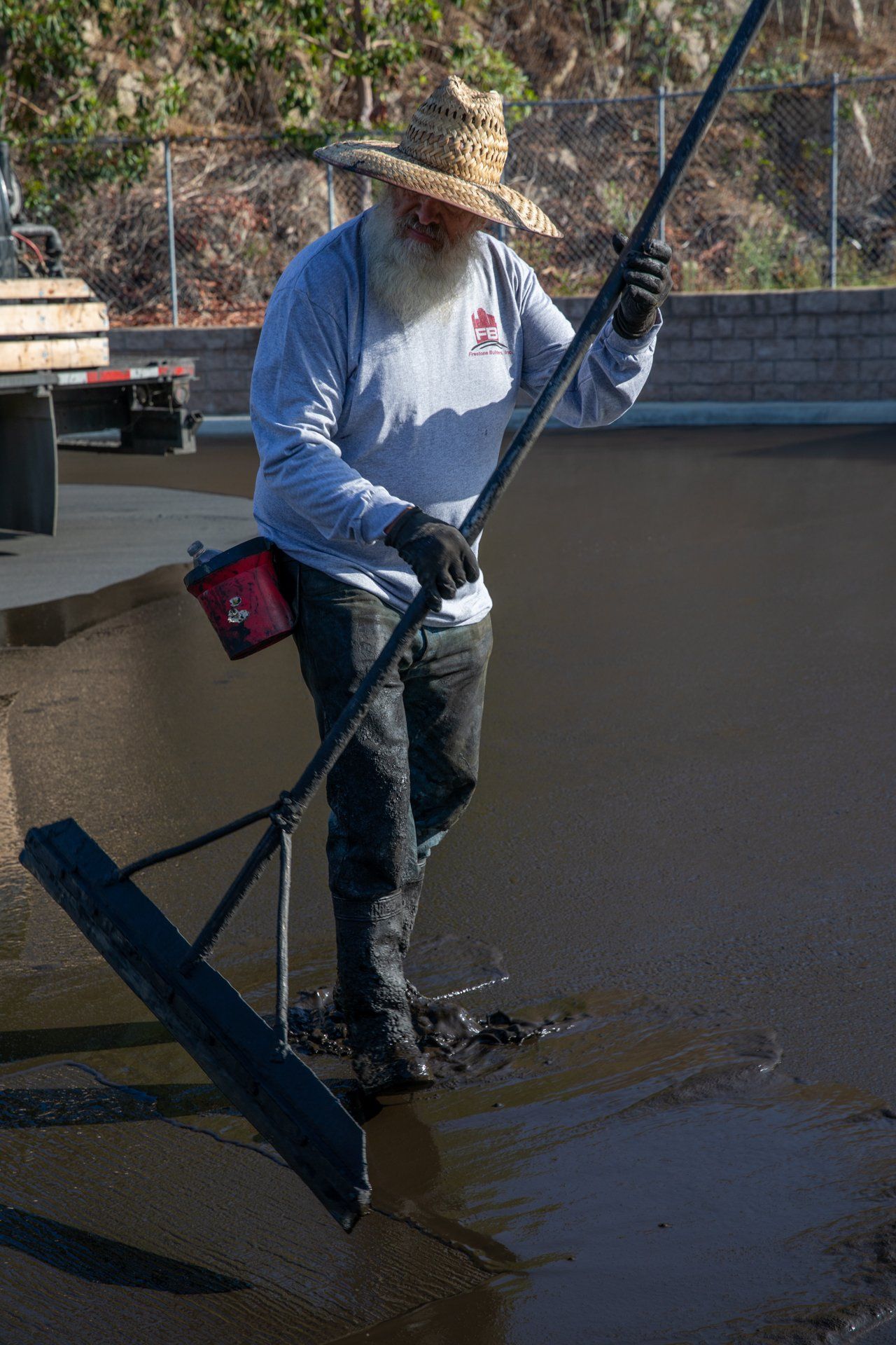 A man with a beard is using a broom to clean a pool of water.