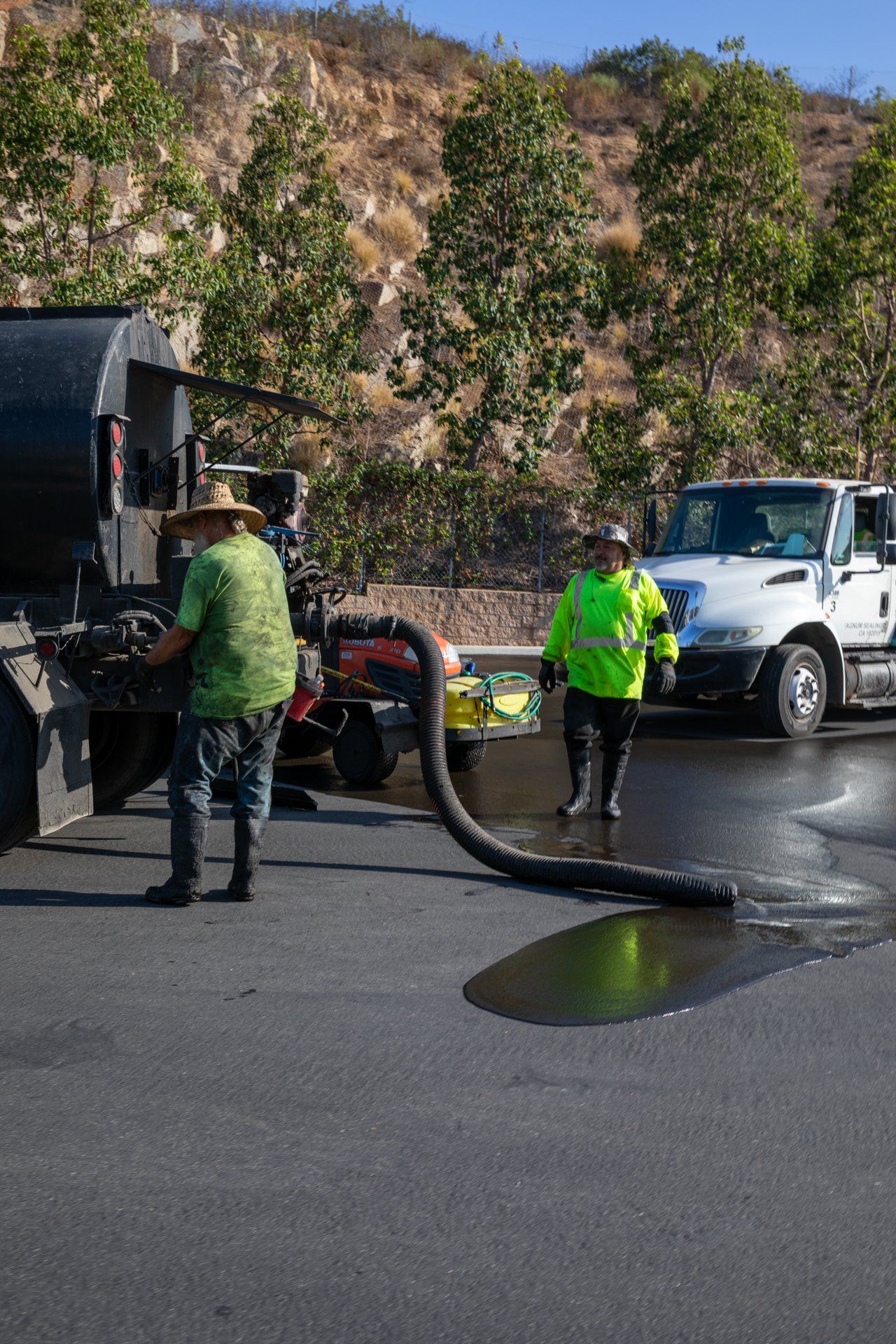 A man is standing next to a truck with a hose attached to it.