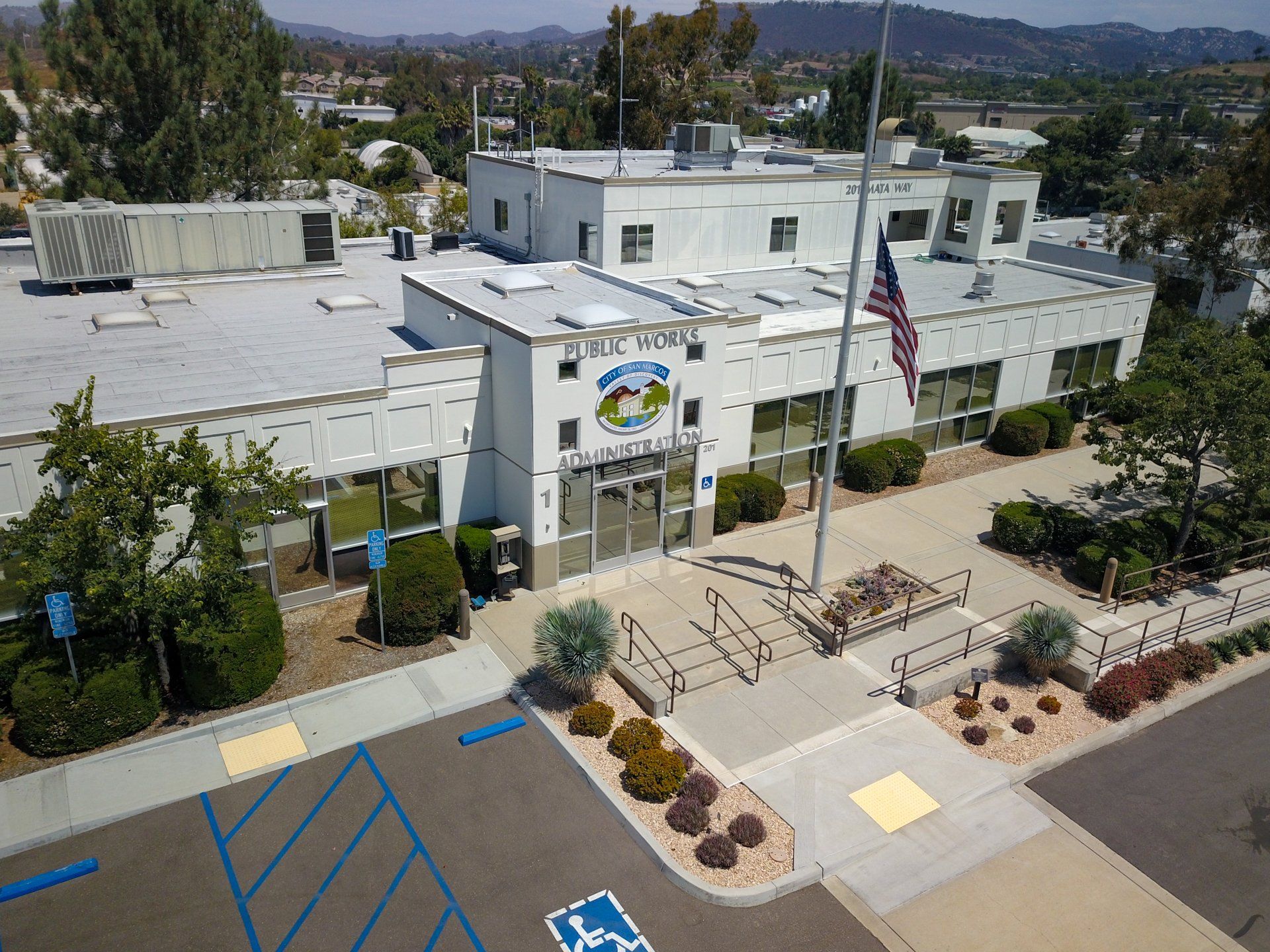 An aerial view of a large white building with a flag pole in front of it.