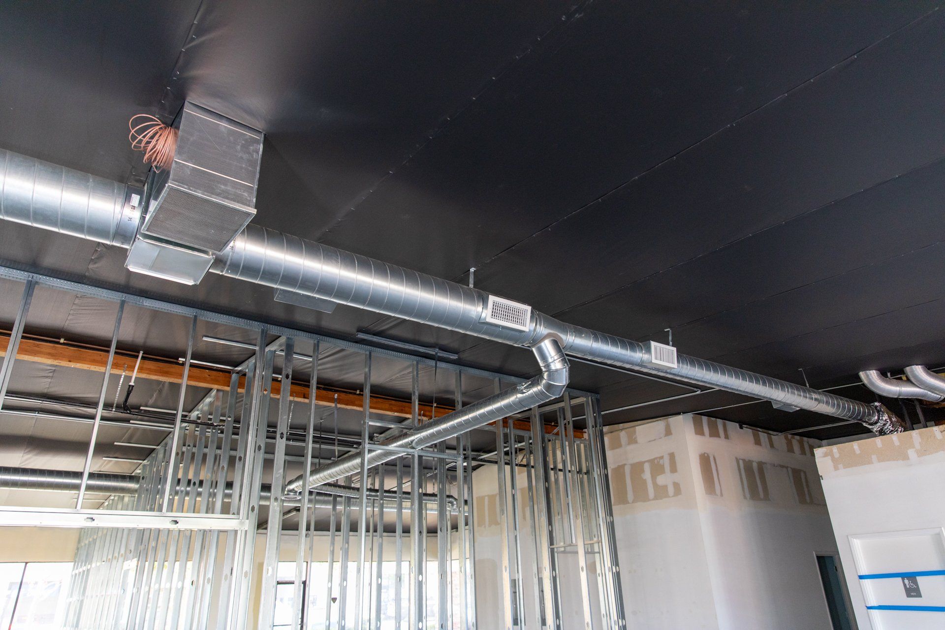 A building under construction with a lot of pipes hanging from the ceiling.