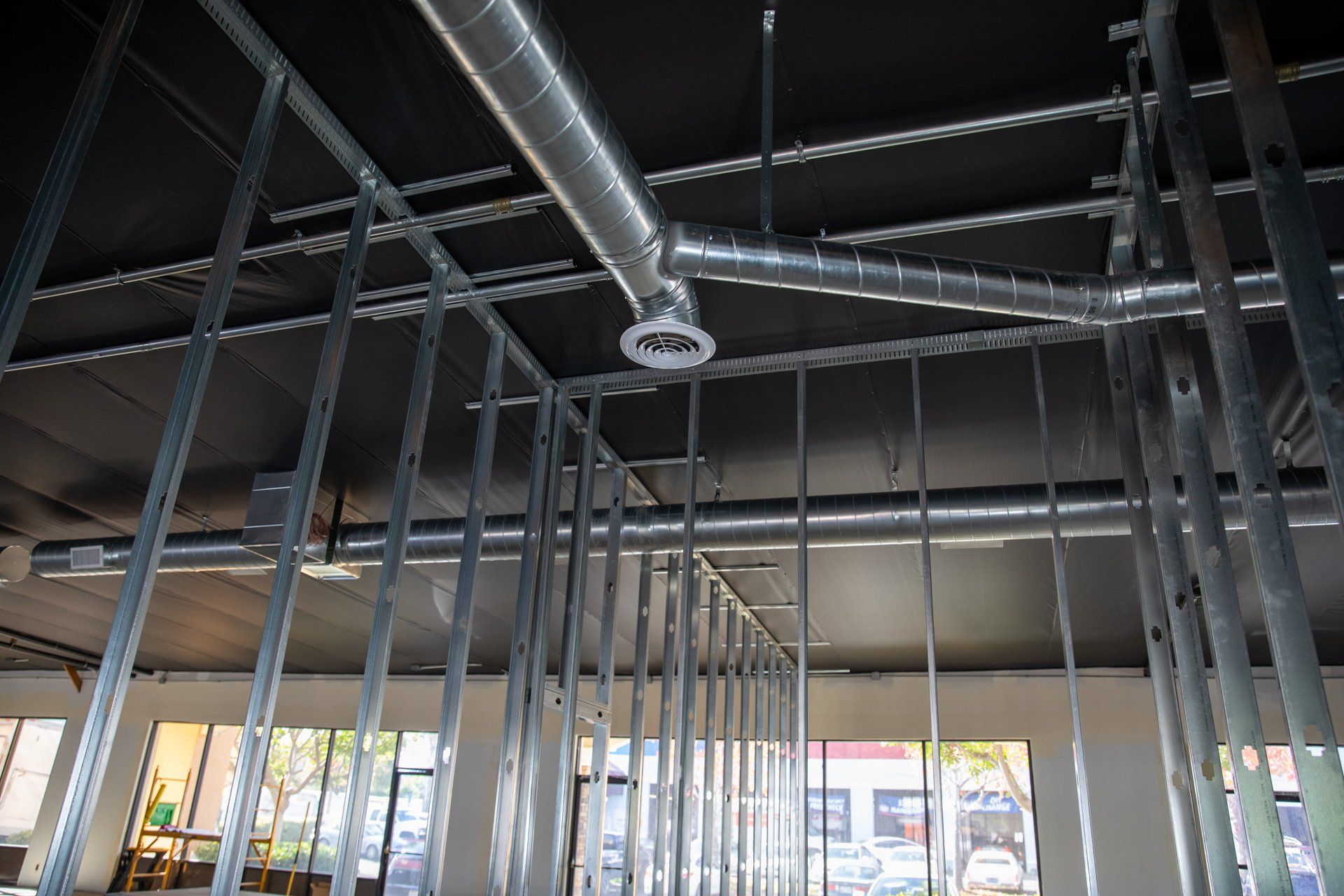 A building under construction with a lot of pipes hanging from the ceiling.