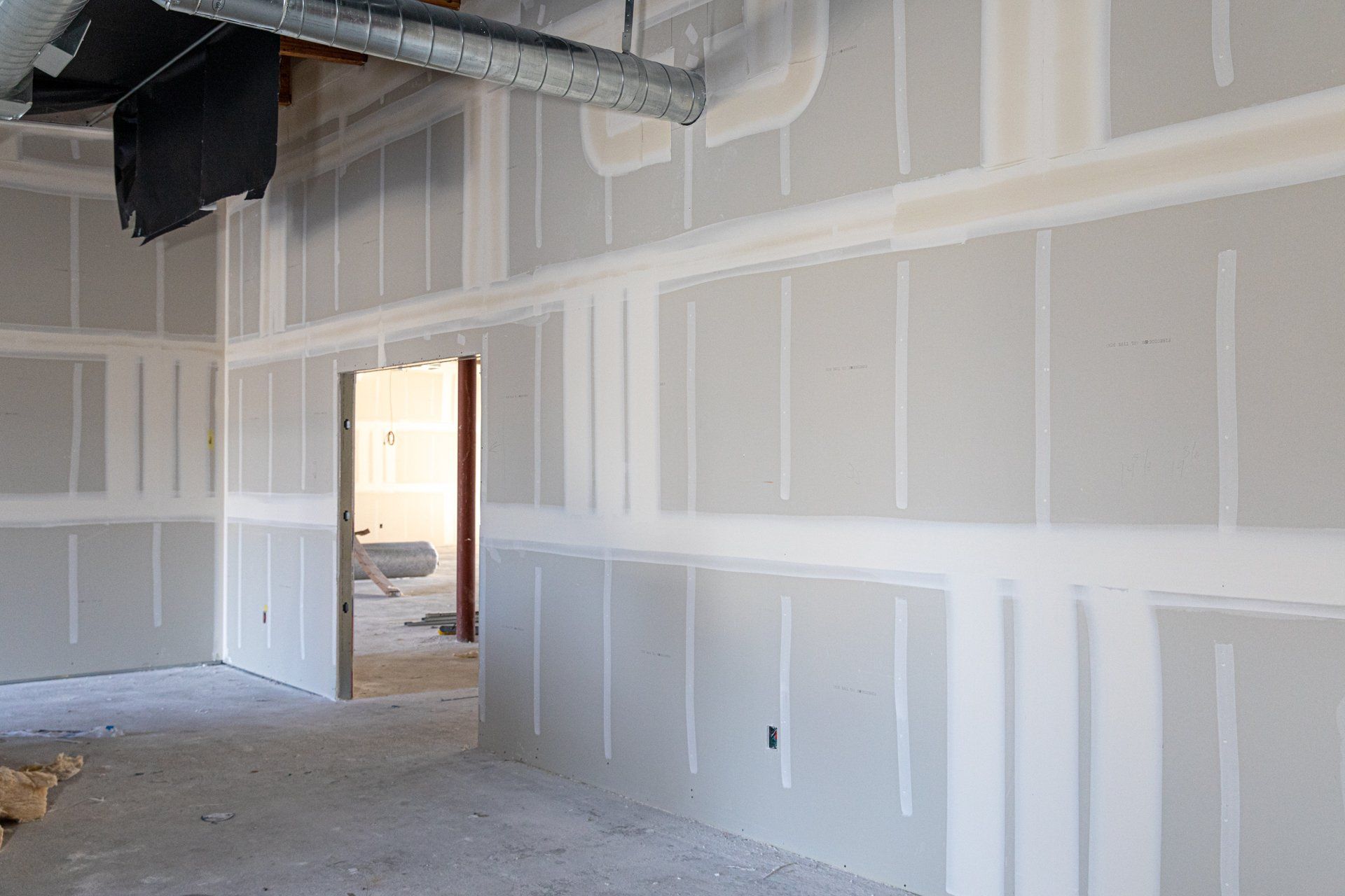 An empty room with drywall walls and a door.