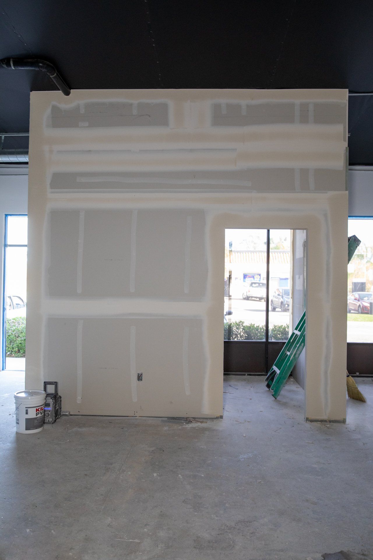 An empty room with a ladder and buckets of paint