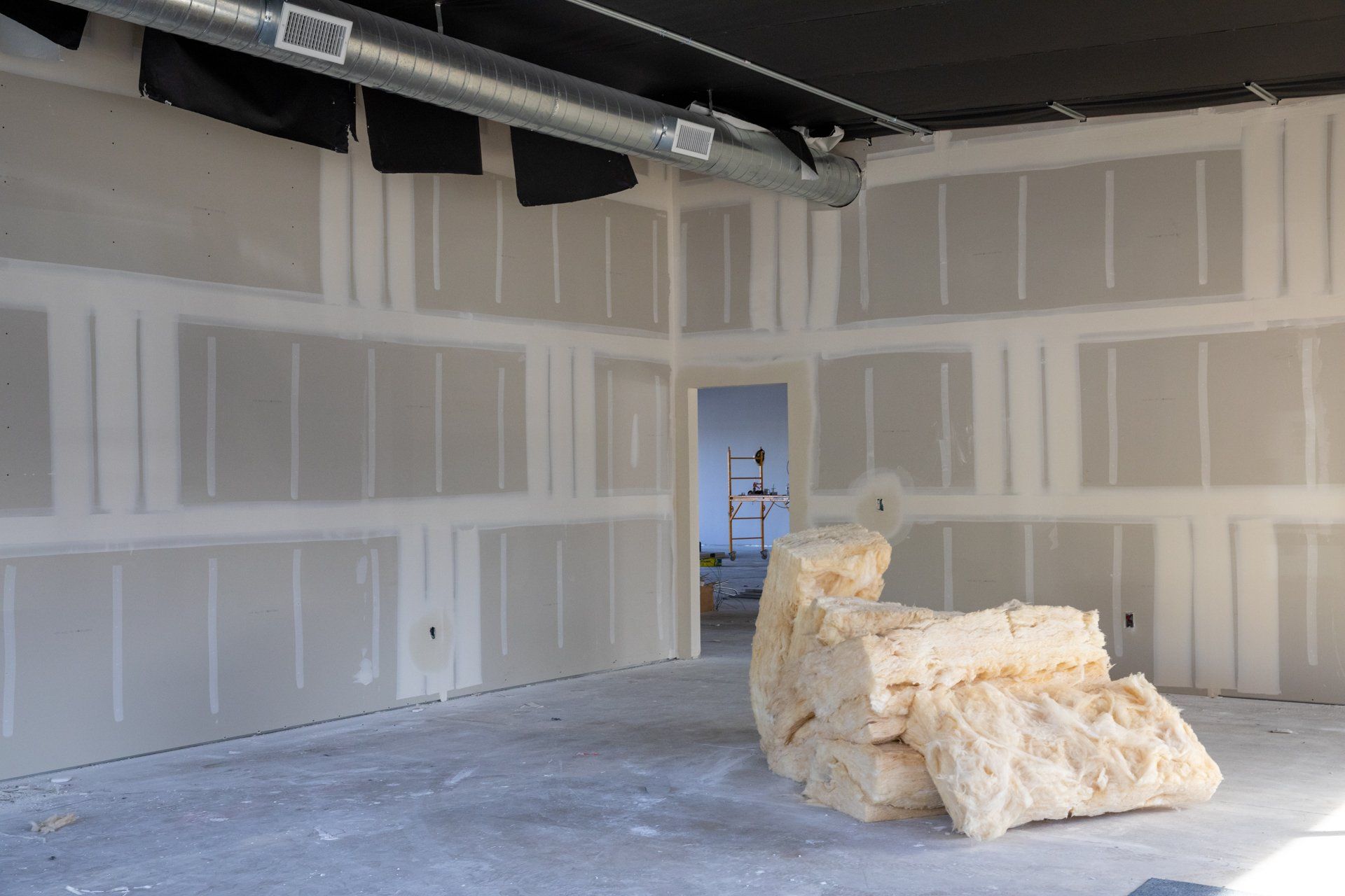 An empty room with a stack of insulation on the floor.