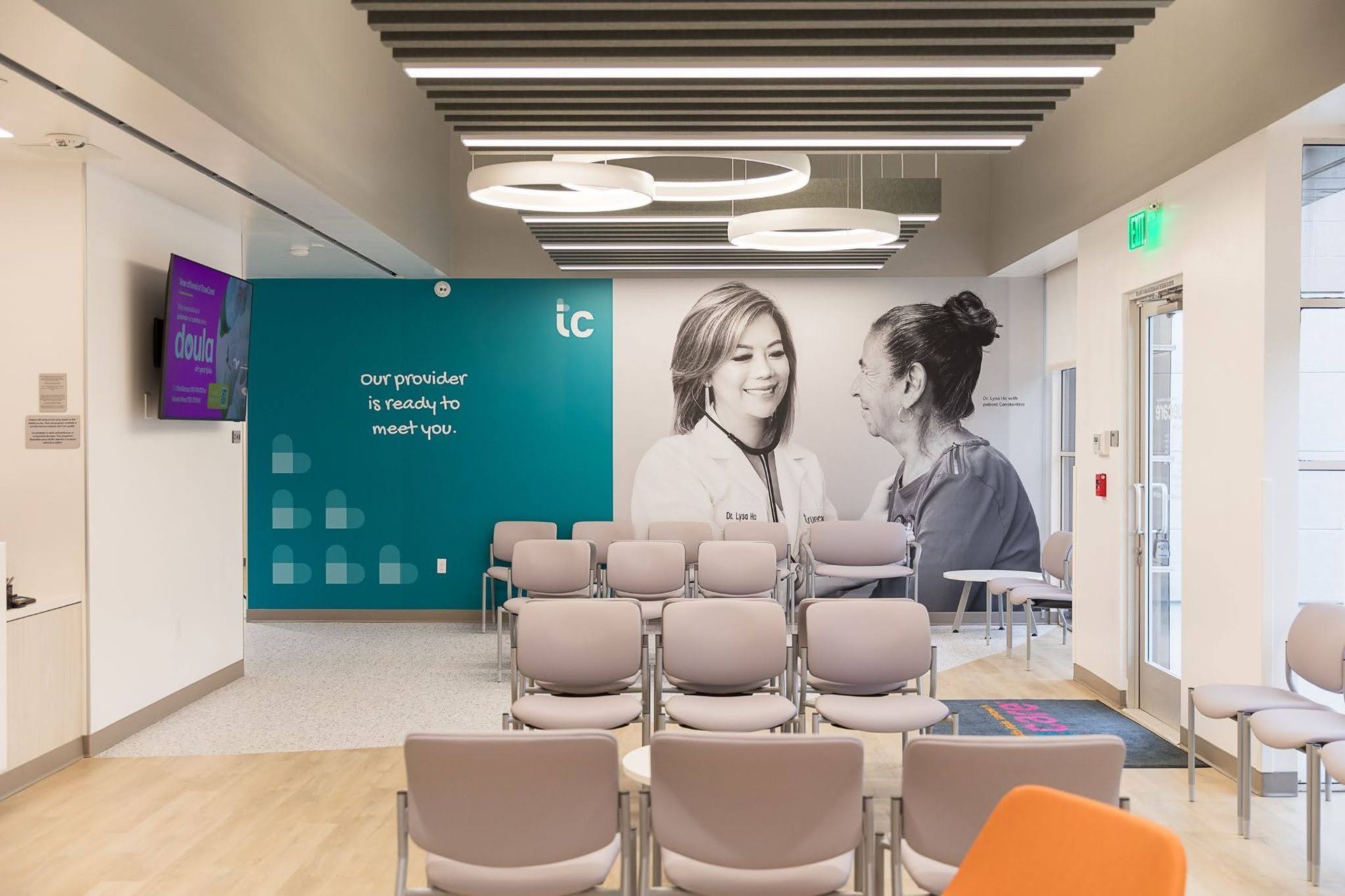 Modern clinic waiting room with beige chairs and a large teal wall mural of two people talking