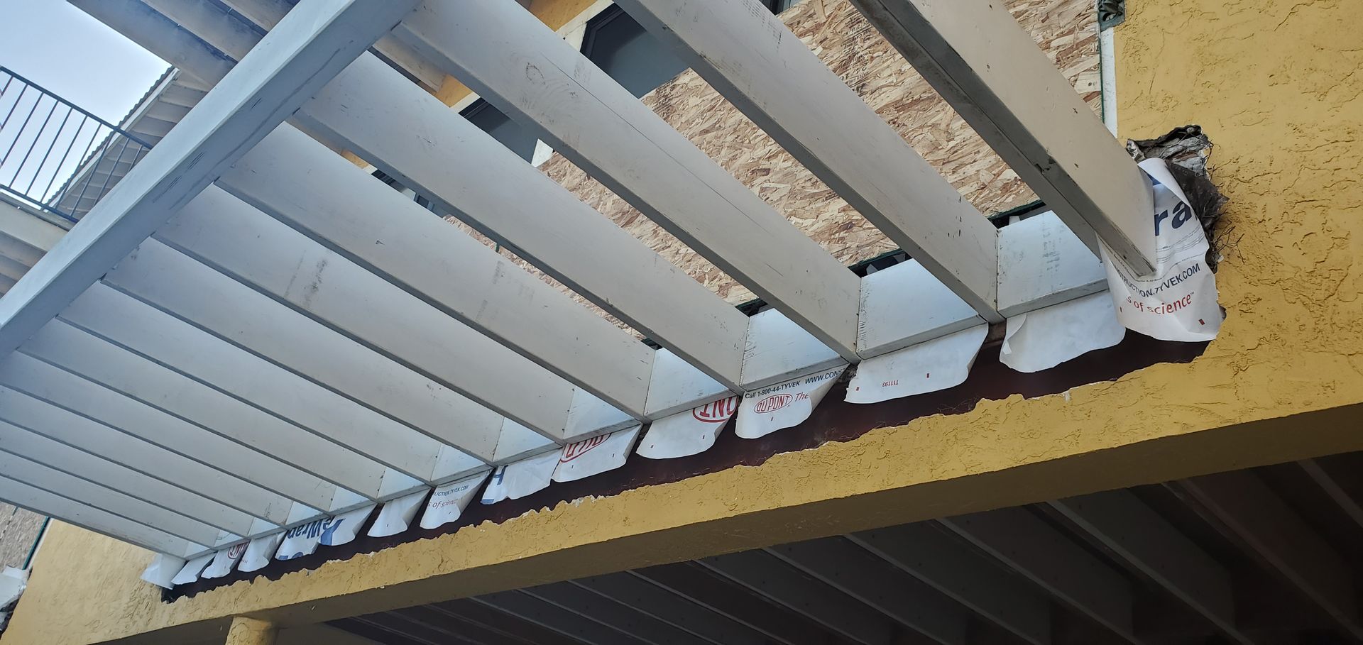 A balcony with a white railing and a yellow wall