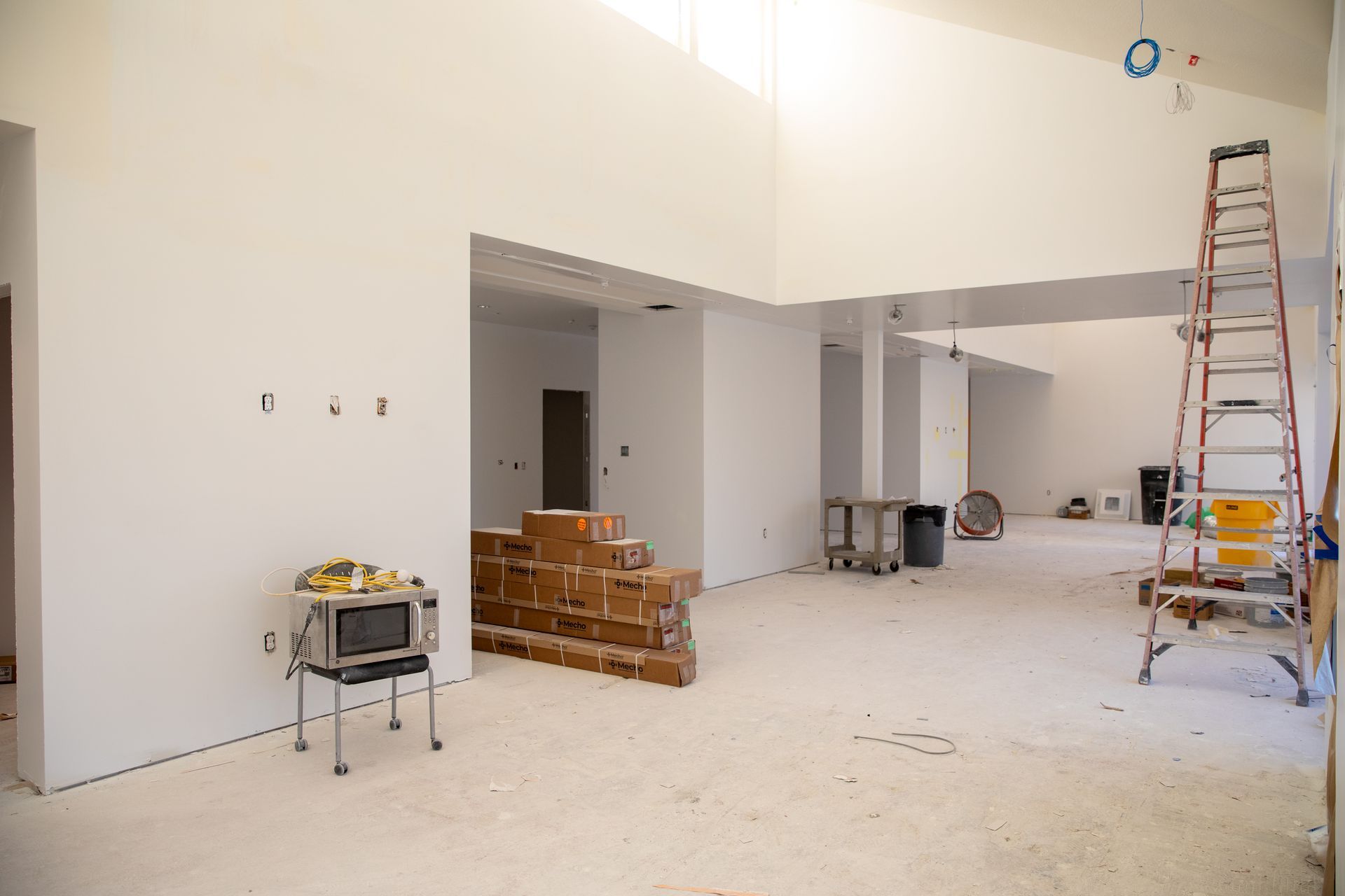 A large room with white walls and a ladder.