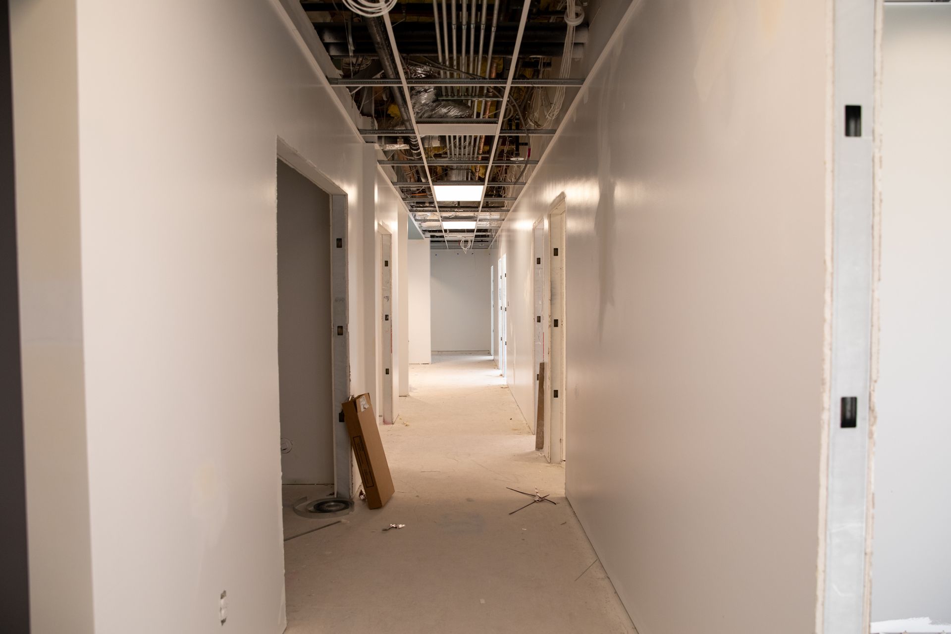 A long hallway with white walls and doors in a building under construction.