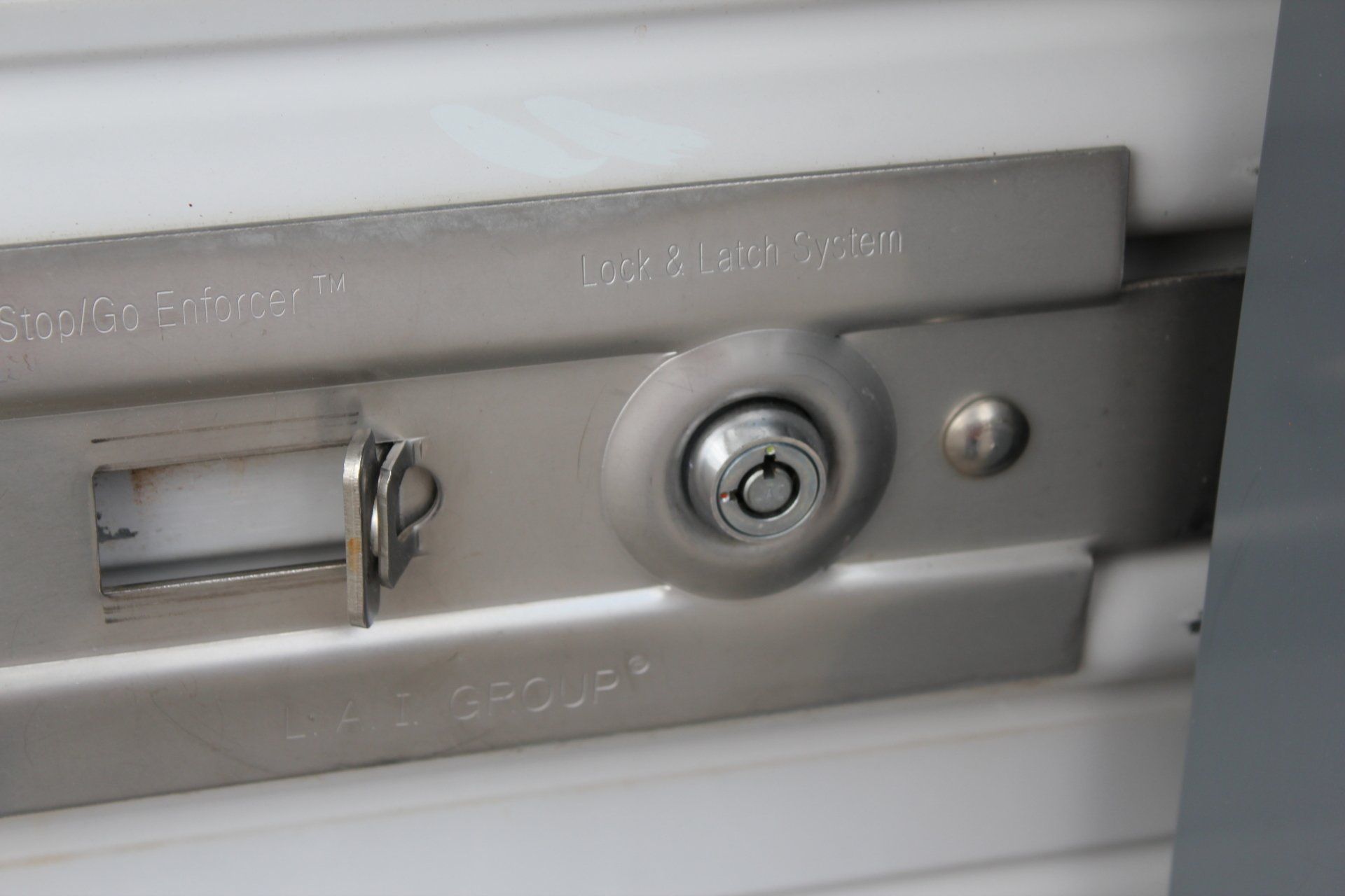 Close-up of a silver metal lock on a white surface. The lock has a keyhole and a latch.