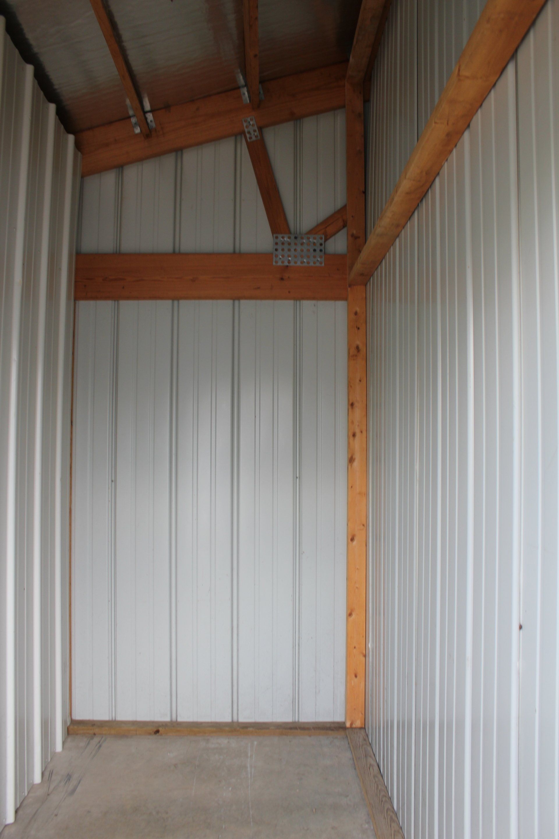 Interior of a storage shed with metal walls and wooden beams.