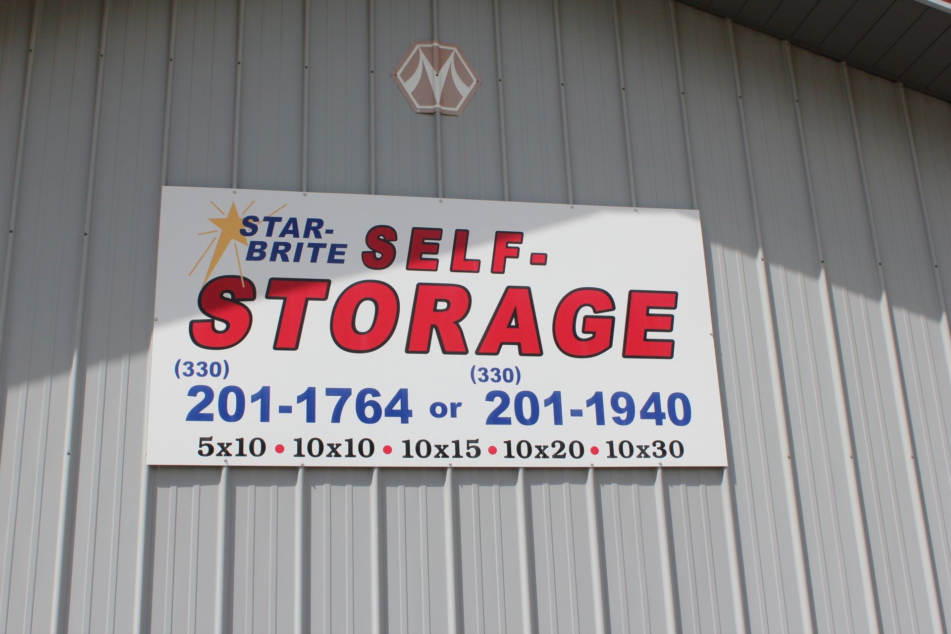 Sign for Star-Brite Self-Storage with contact info and unit sizes on a corrugated building.