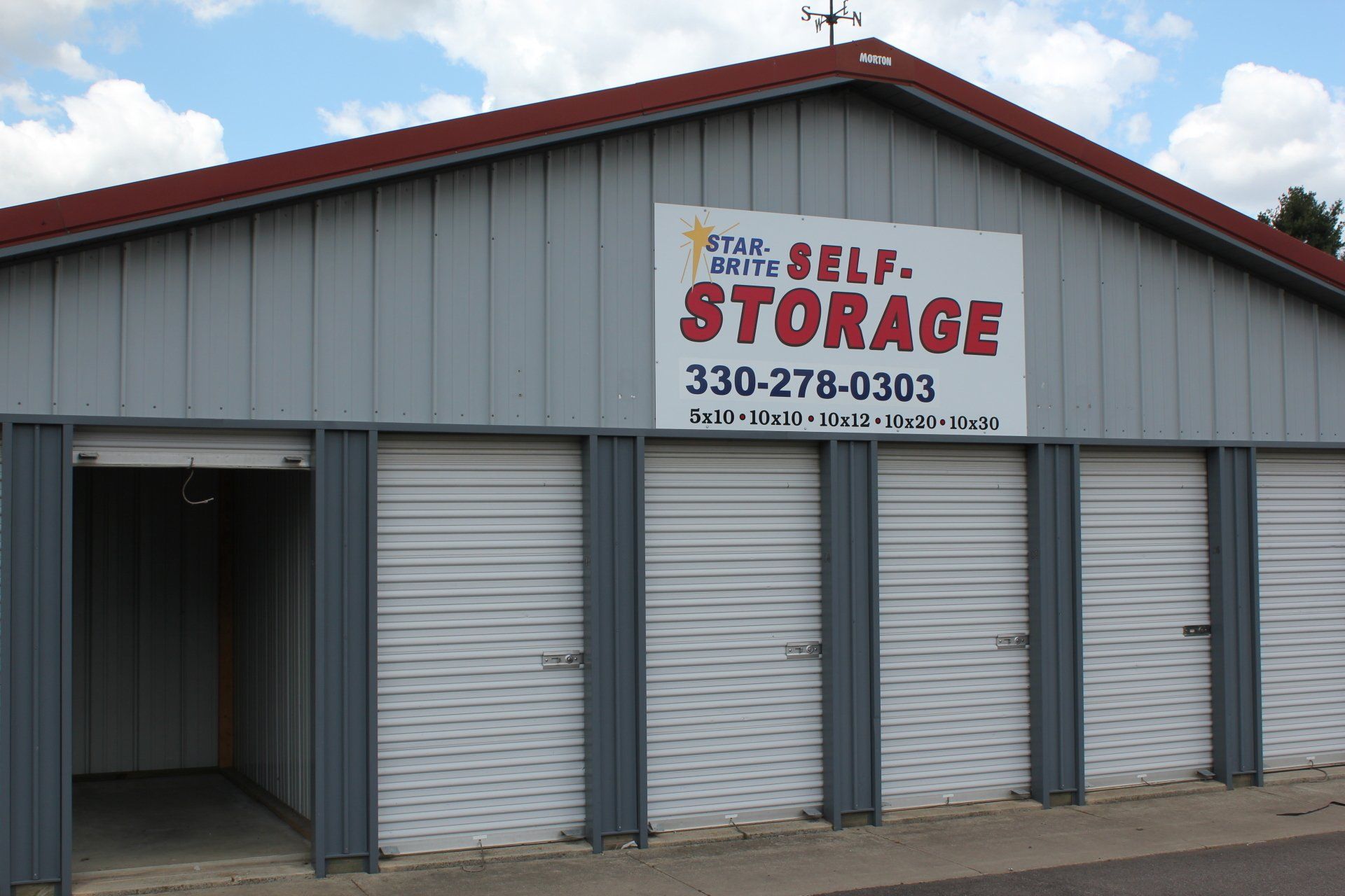 Gray Utah Self-Storage building with roll-up doors. Sign with phone number.