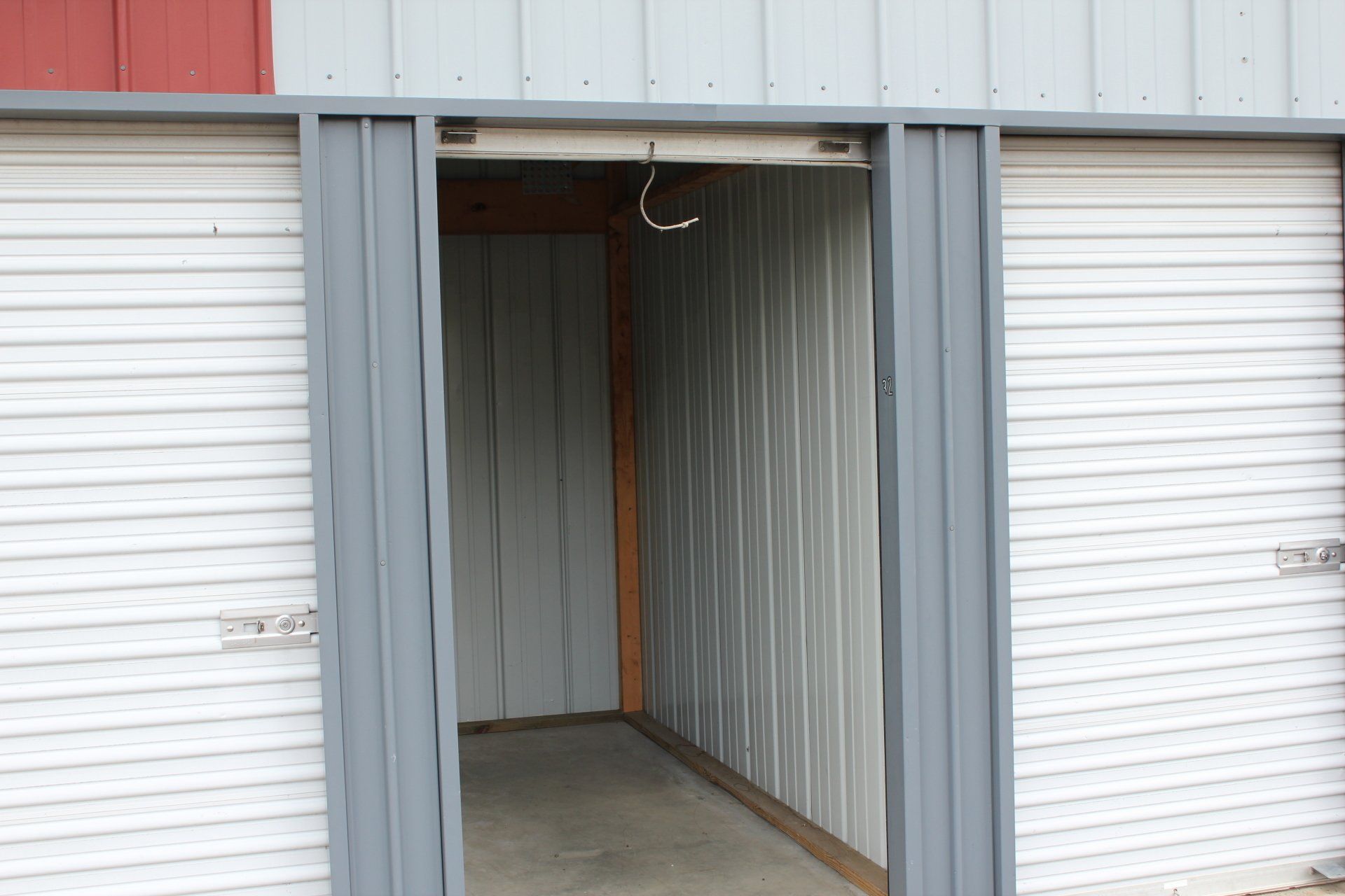 Open storage unit with roll-up door, gray metal siding, and a visible interior.