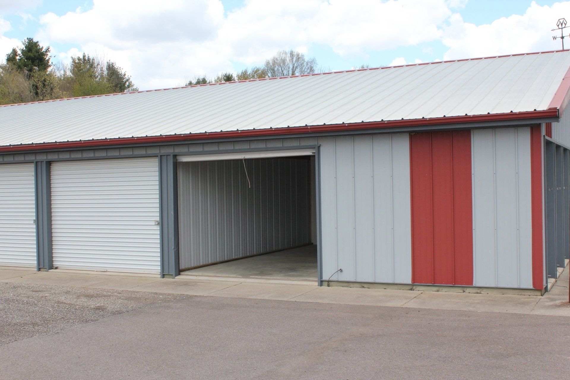 Storage units with gray and red metal siding, open unit visible.