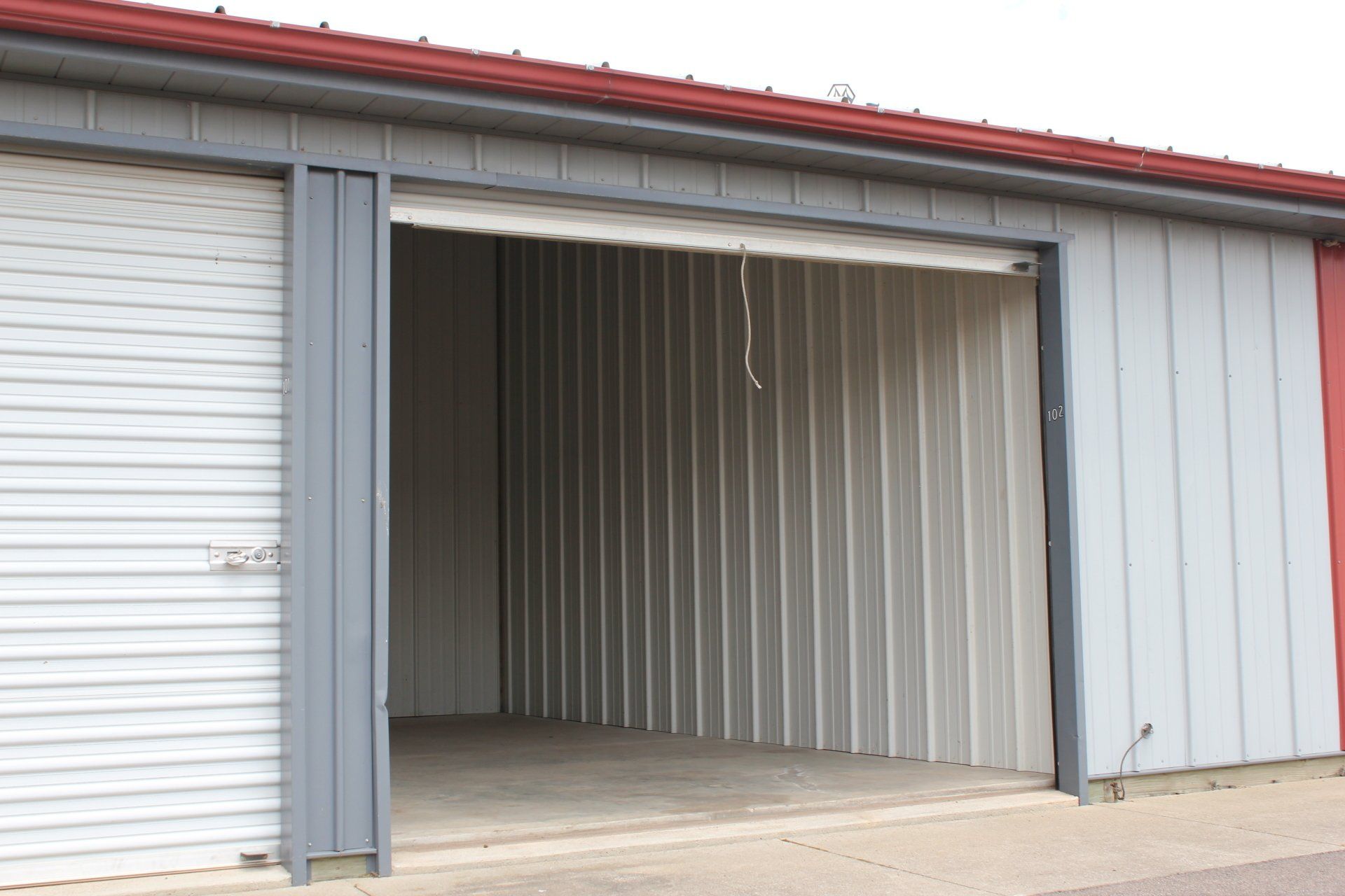 Storage unit with a partially open gray metal door.