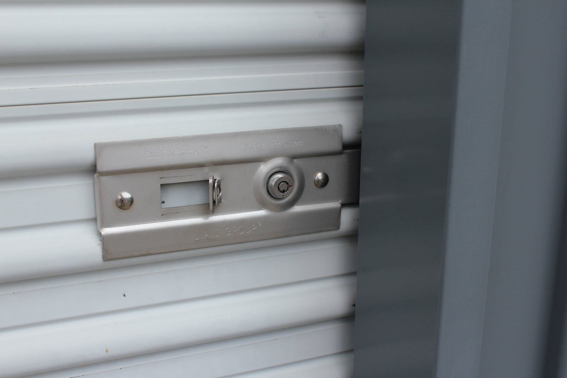 Close-up of a metal lock on a white, slatted roll-up door.