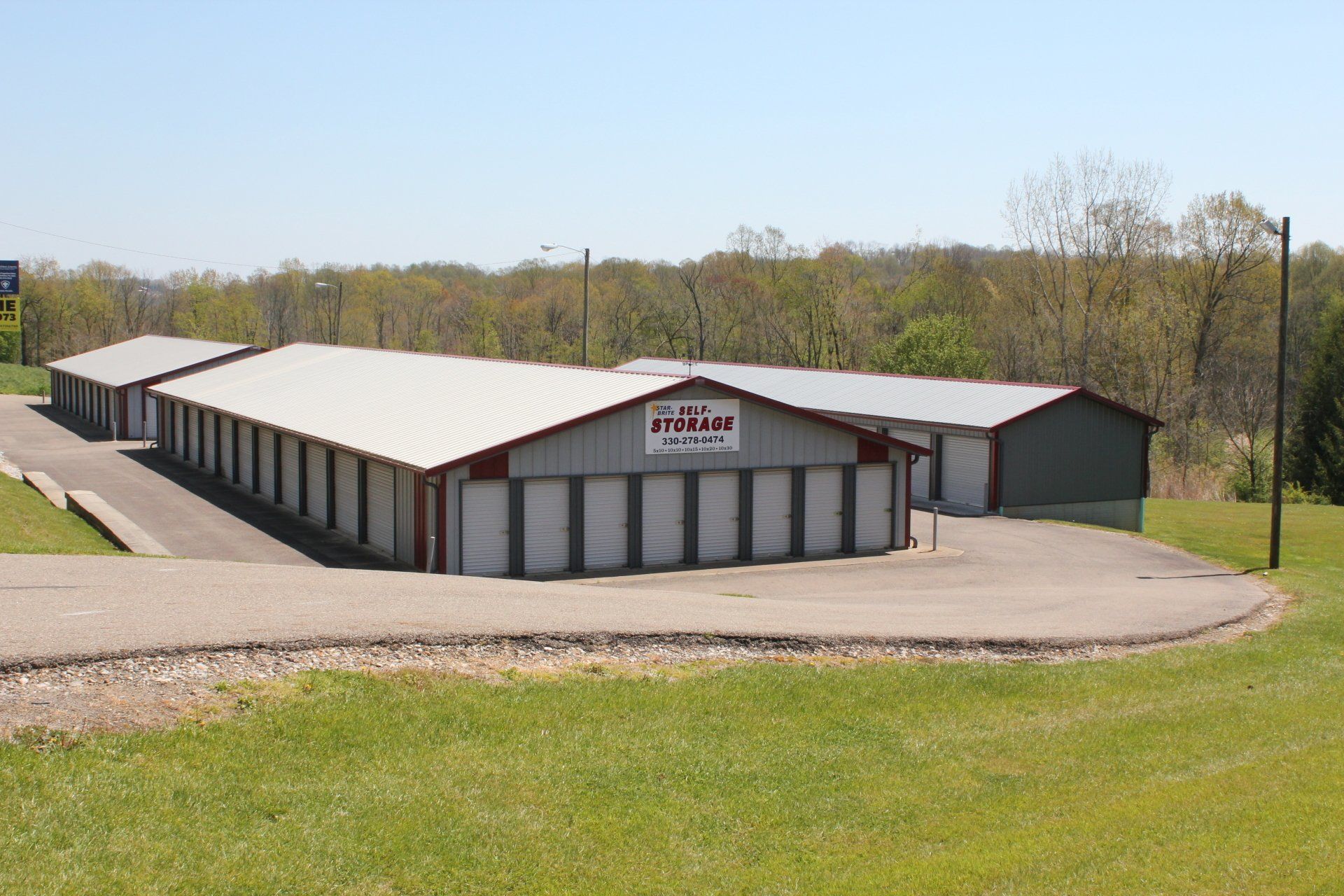 Storage facility buildings with white doors and red trim on a sunny day.