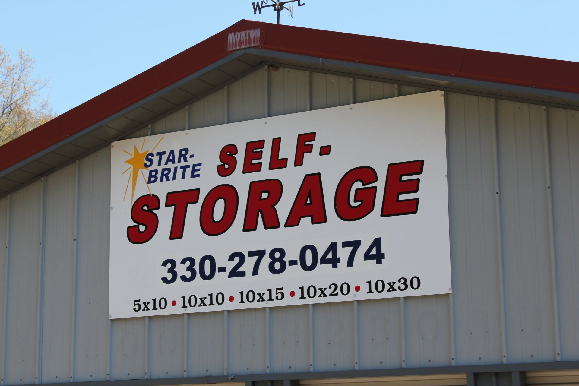 Sign for Star-Brite Self-Storage with phone number and unit sizes, on a building.