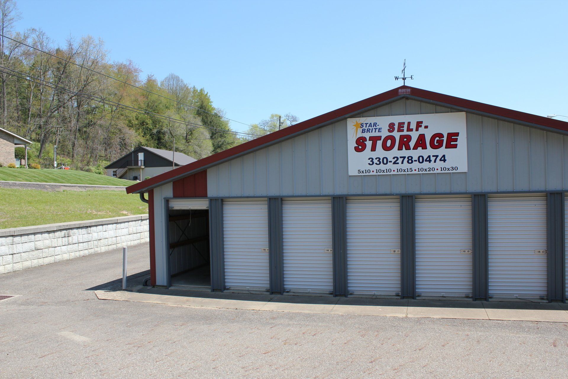 Storage units building with gray doors and red roof; sign says 