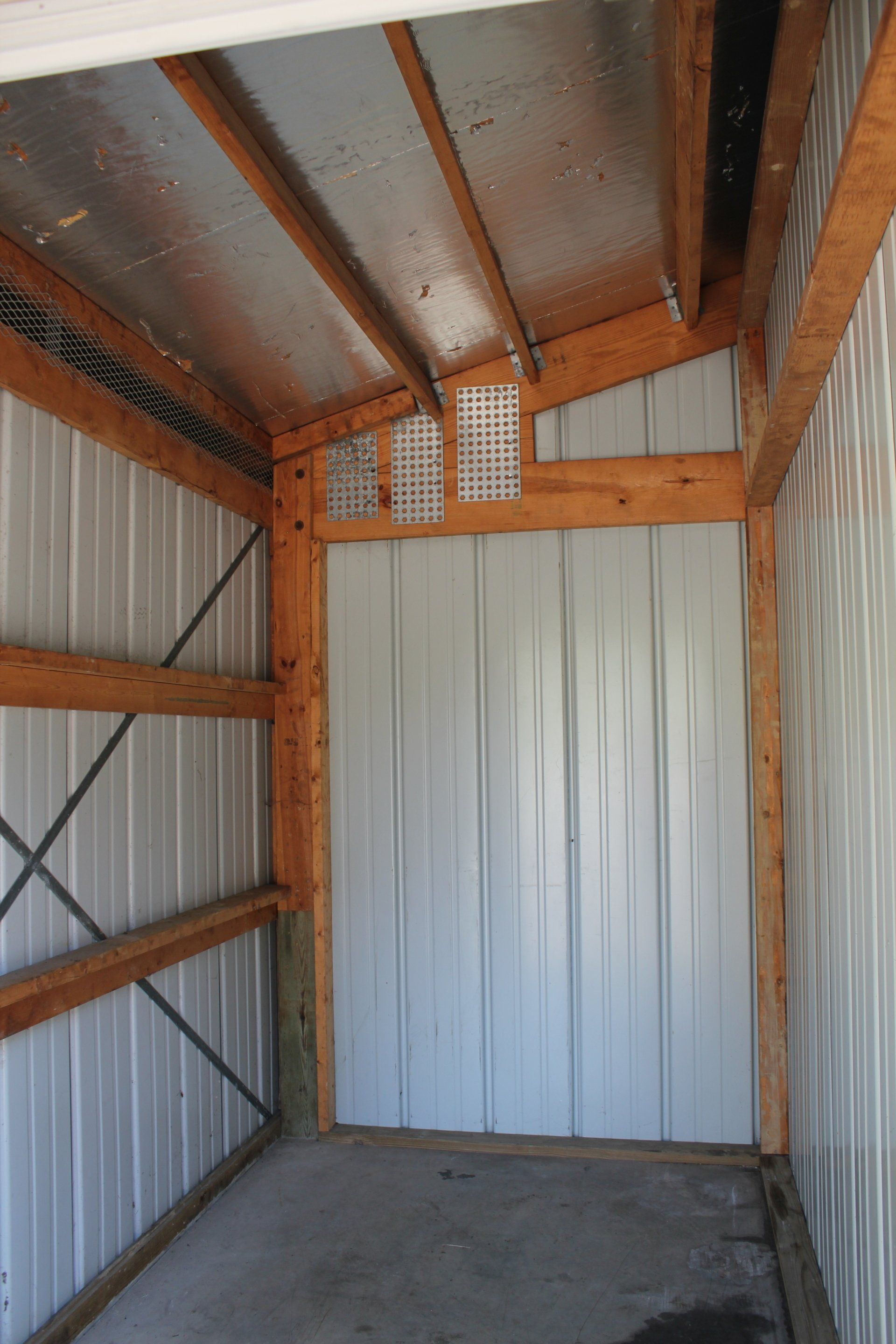Interior of a metal storage shed with wood framing and corrugated metal walls.