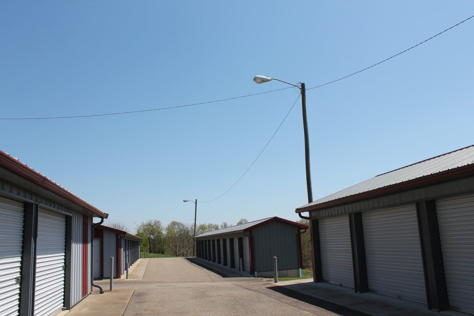 Rows of storage units with gray doors and red trim under a blue sky.