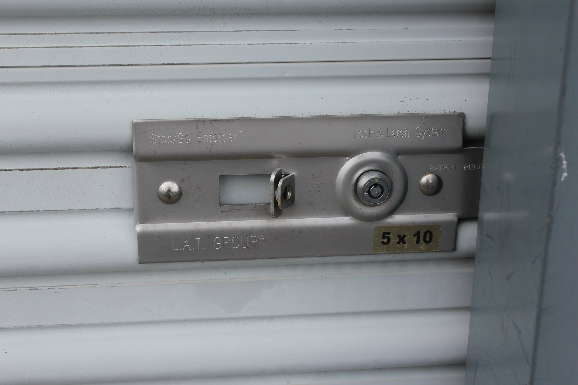 Metal storage unit door latch with a key lock.