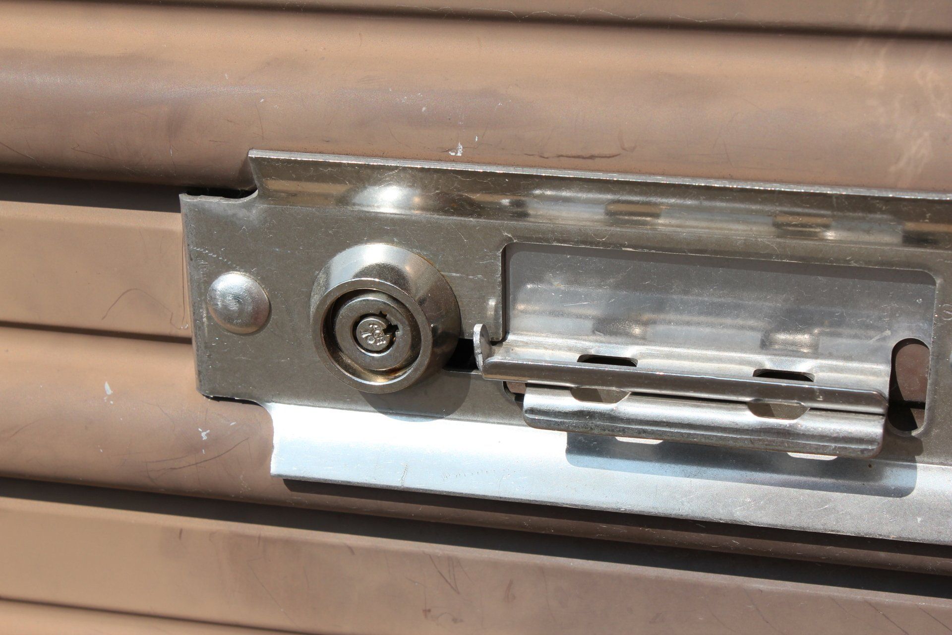 Close-up of a metal lock mechanism on a brown corrugated surface.