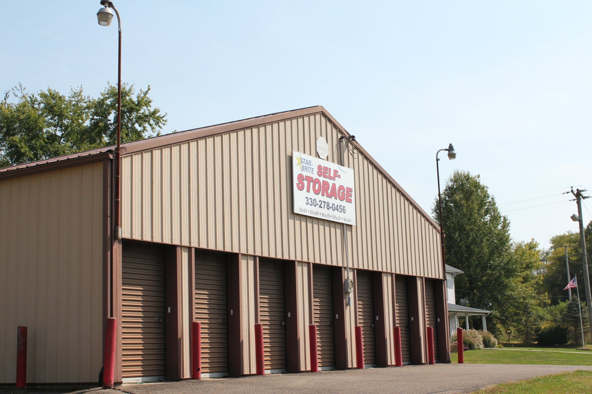 Self-storage building with beige siding and multiple roll-up doors. A sign reads 