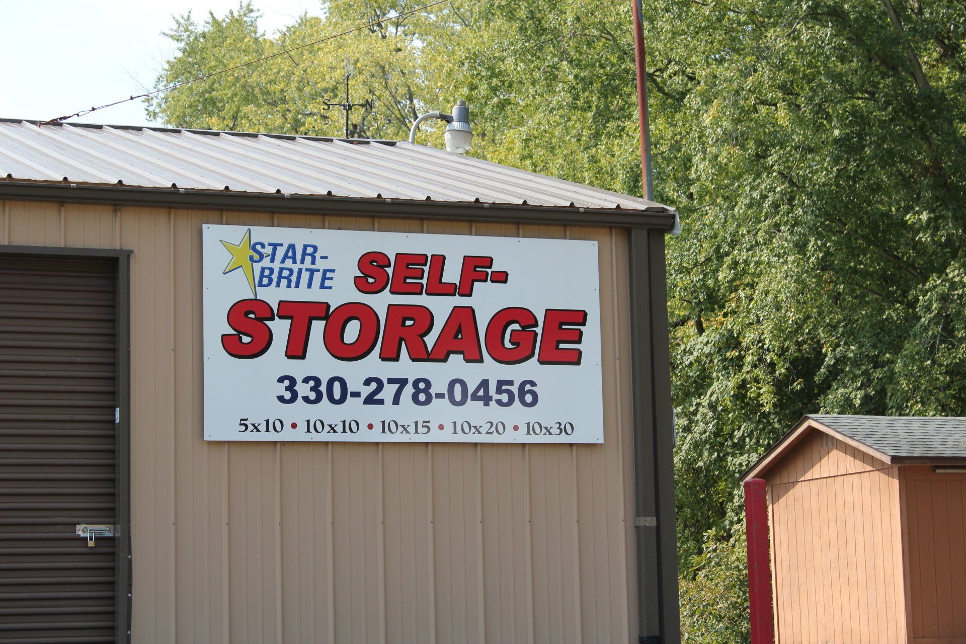 Sign for Star-Brite Self-Storage, beige building with red and blue lettering, phone number, and unit sizes.