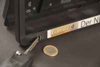 Ein Autoschlüssel liegt neben einer Münze und einem Nummernschildrahmen.