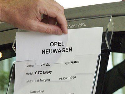 Eine Person hält einen Zettel mit der Aufschrift „Opel Neuwagen“.
