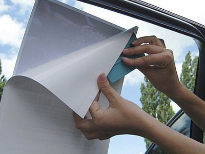 Eine Person zieht ein Stück Papier aus einem Autofenster.