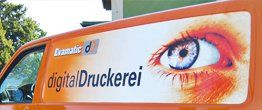 Ein orangefarbener Lieferwagen mit einem Auge und dem Schriftzug „digitaldruckerei“ auf der Seite