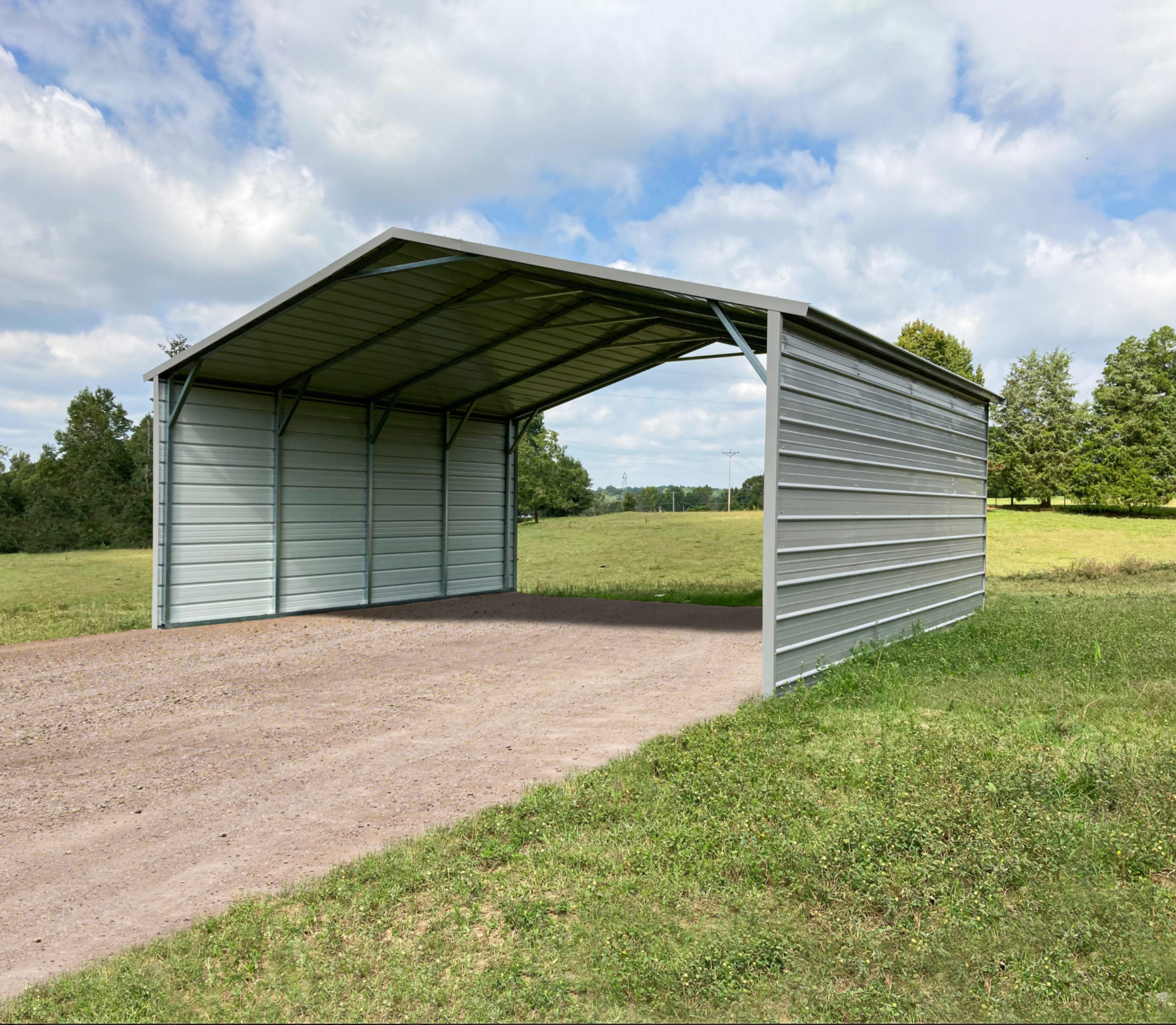 Metal carport on gravel driveway in a grassy field under a cloudy sky.
