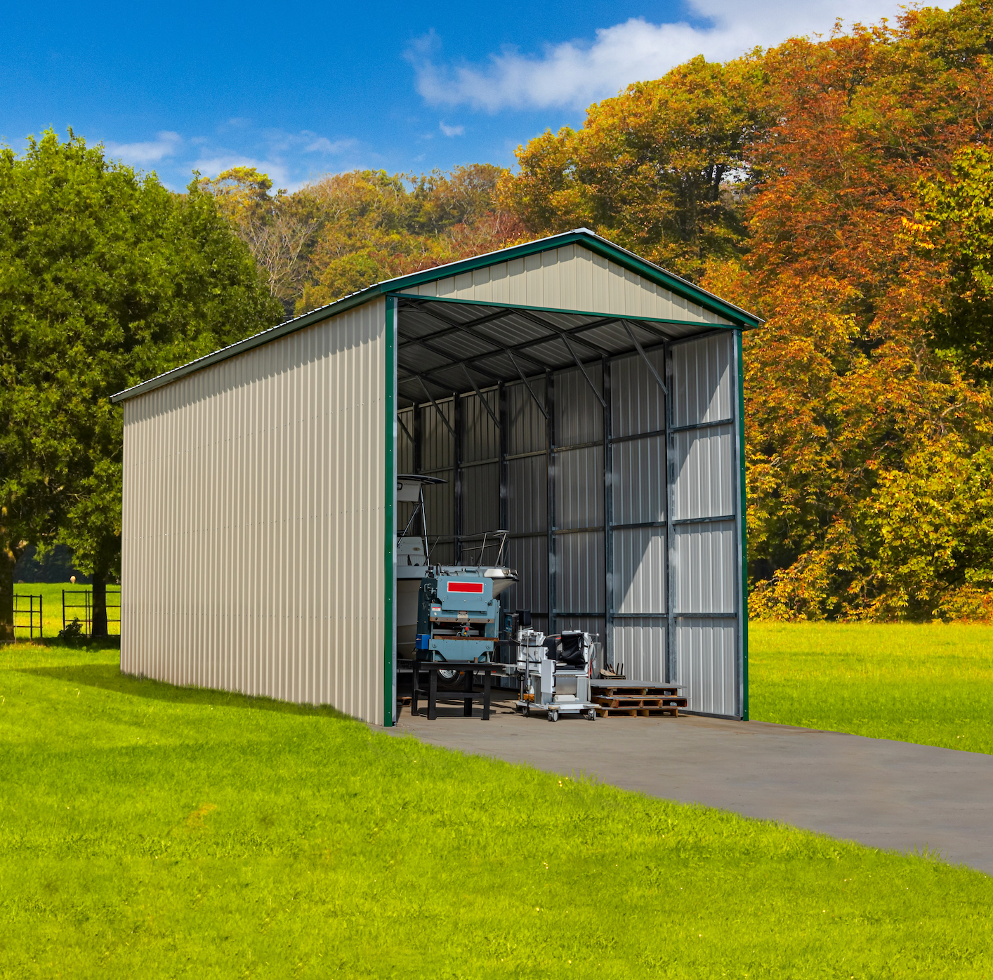 Metal shed with green trim and open front on a grassy lawn. Equipment inside. Trees in background.