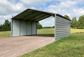 Metal carport on gravel driveway in a grassy field under a cloudy sky.