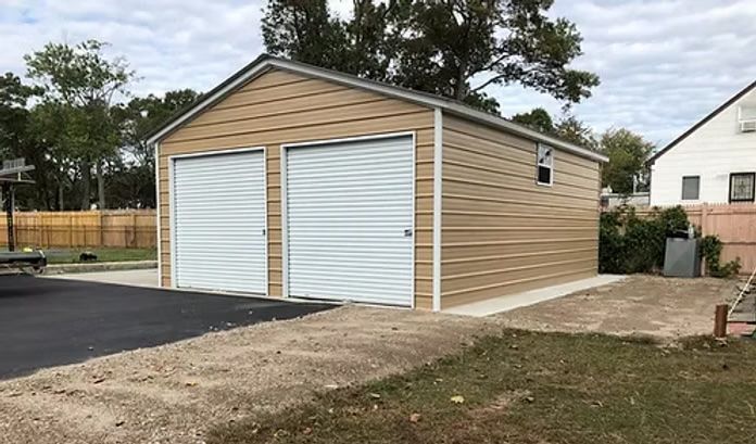 Tan two-car garage with white doors, on a concrete pad, next to a house and driveway.